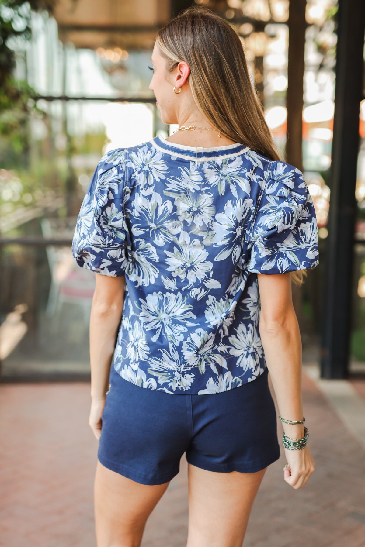Woman wearing a blue floral top and navy shorts in an outdoor setting