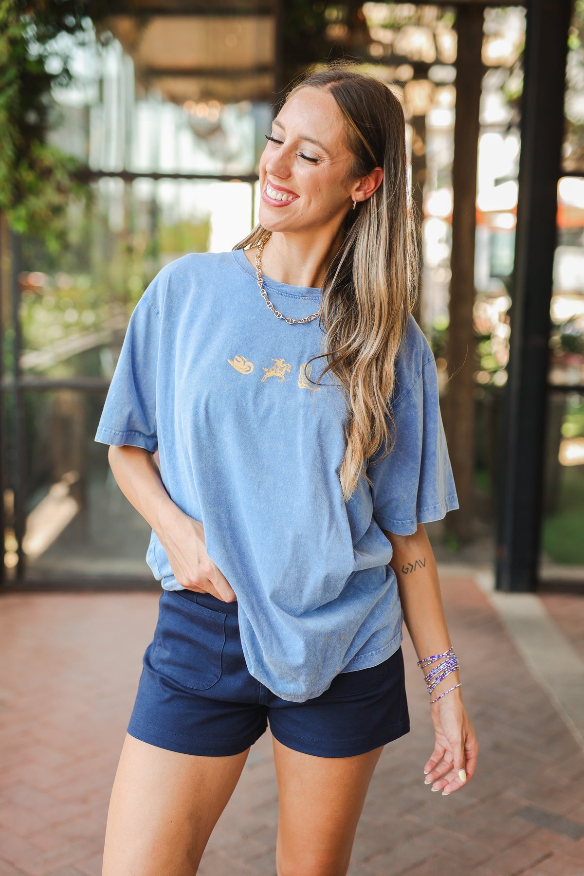 Woman wearing a blue t-shirt and navy shorts outdoors