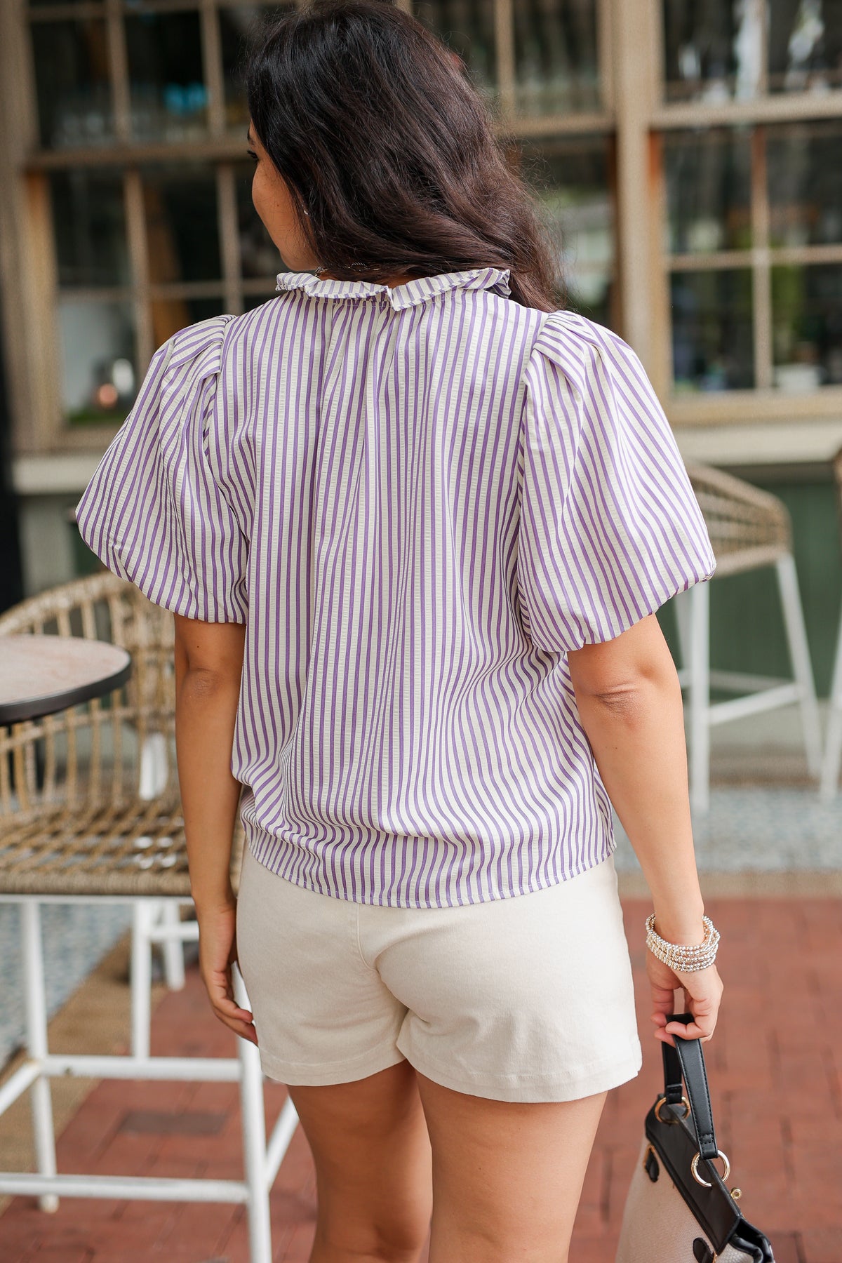 Woman wearing a striped shirt and white shorts standing in an outdoor setting.