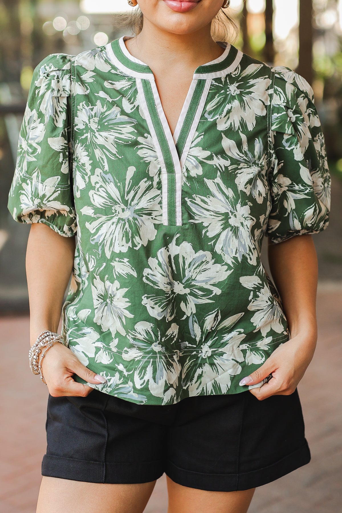 Woman wearing a green floral blouse with black shorts outdoors