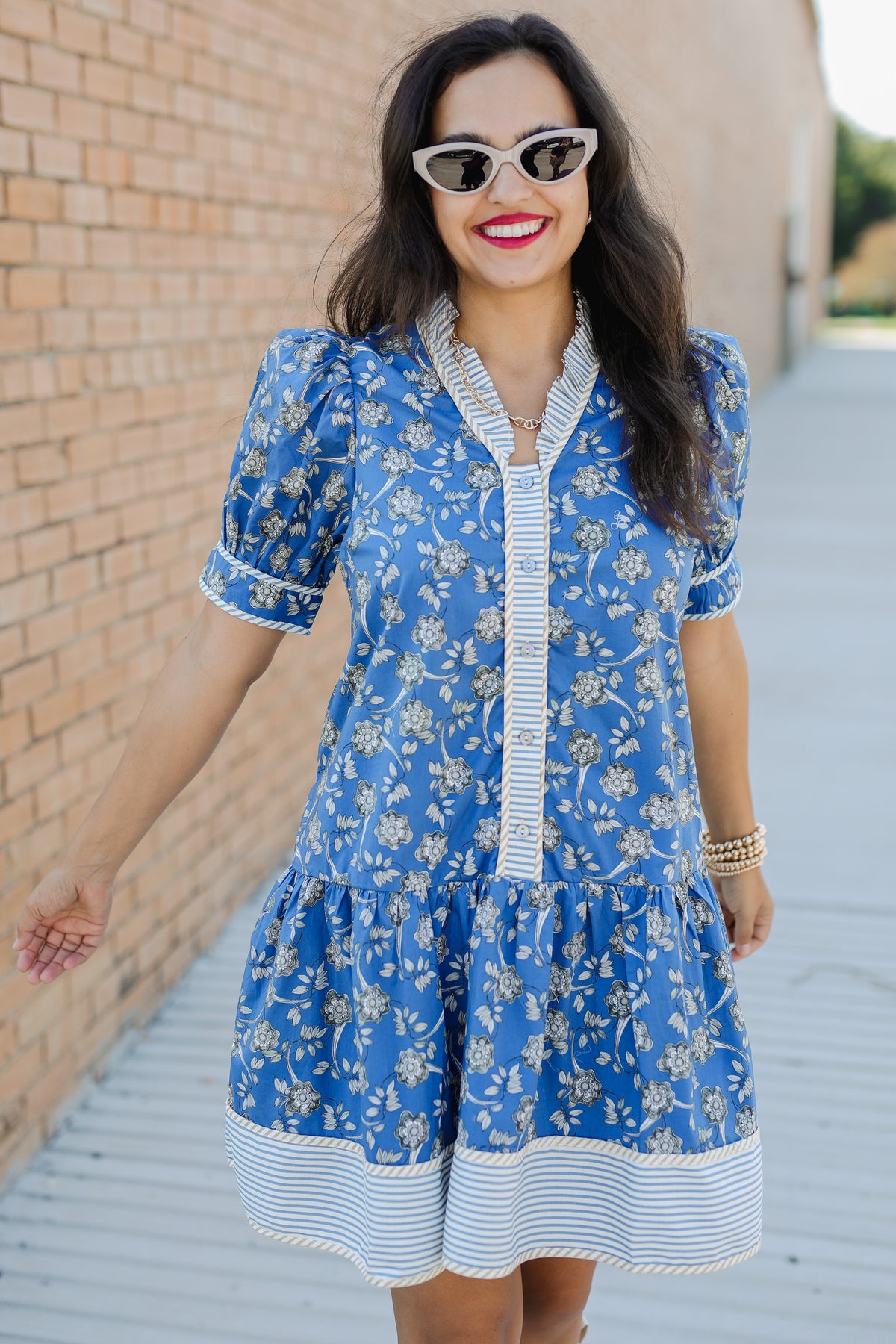 Woman wearing a blue floral dress with a brick wall background