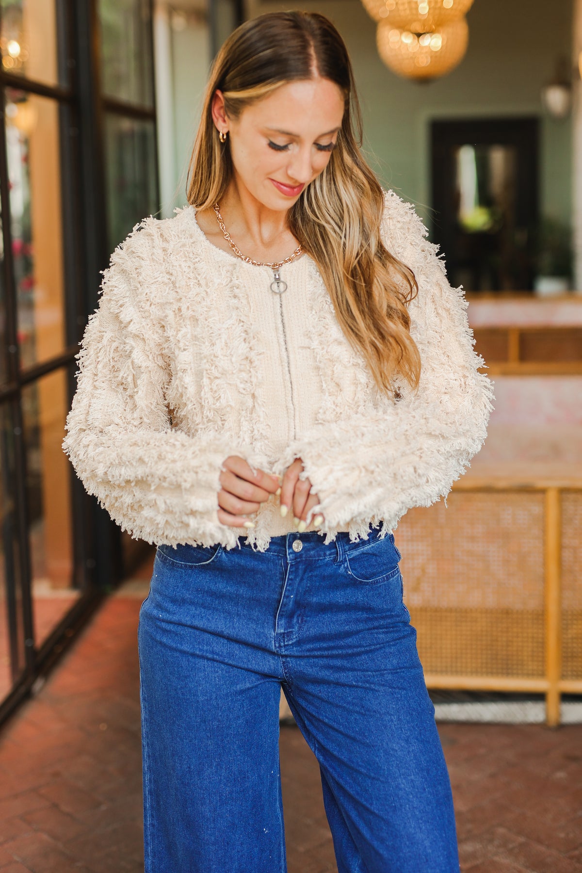 Woman wearing a textured white top and blue jeans indoors.