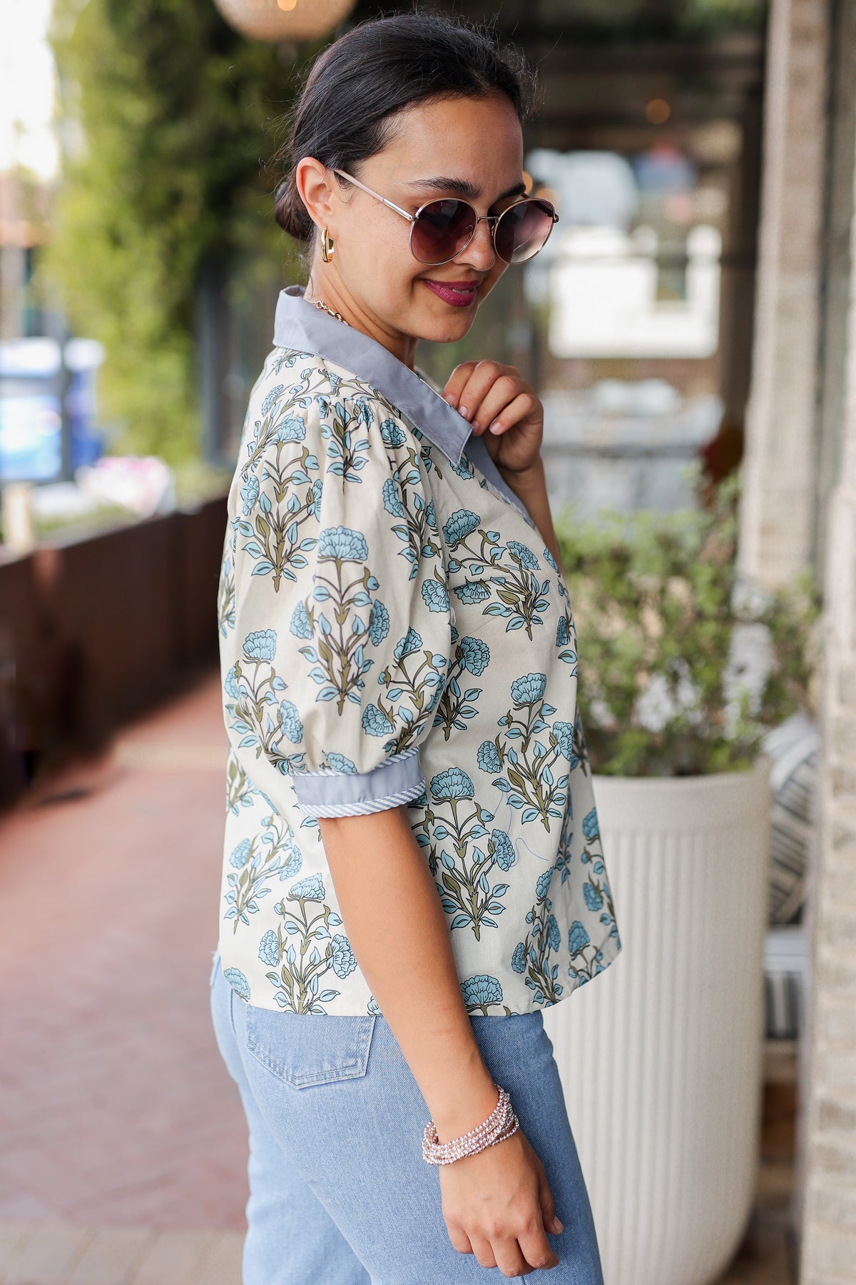 Woman wearing a floral blouse and sunglasses outdoors
