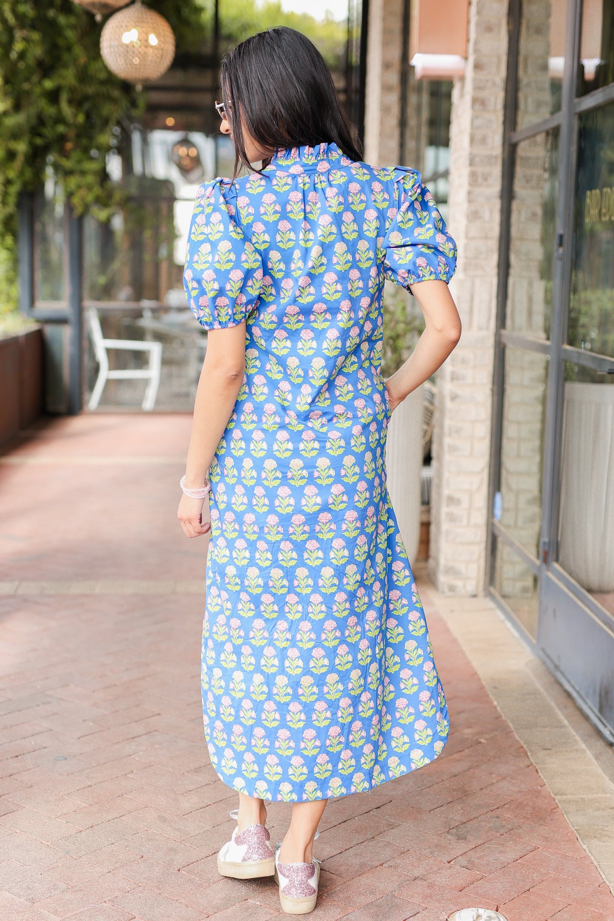 Woman wearing a blue floral dress standing outdoors.