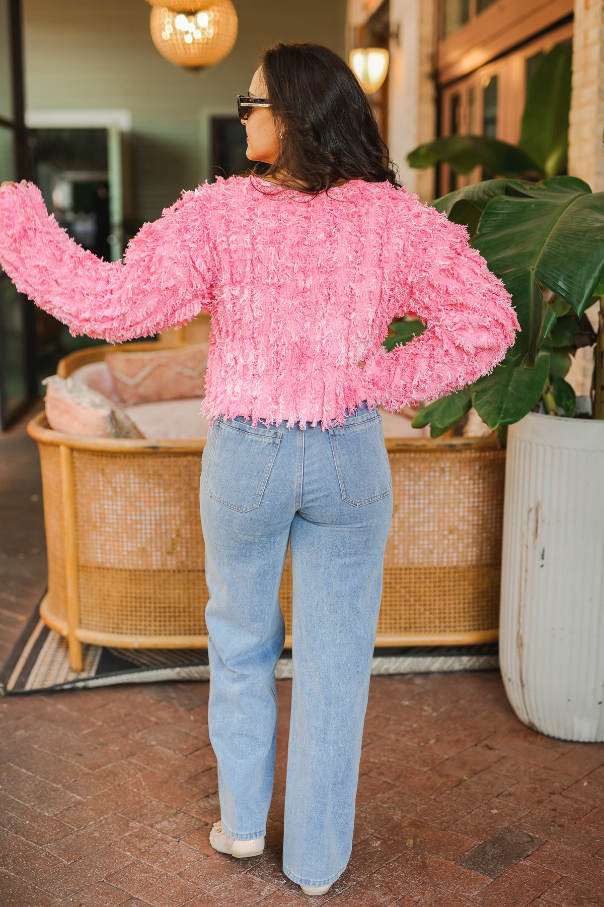 Person wearing a pink textured jacket and light blue jeans in an indoor setting.