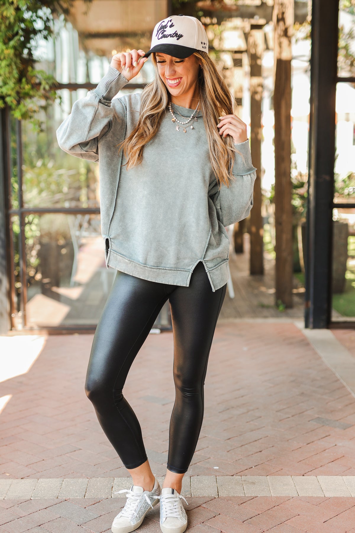 Woman wearing a gray sweatshirt, black leggings, and white sneakers outdoors.