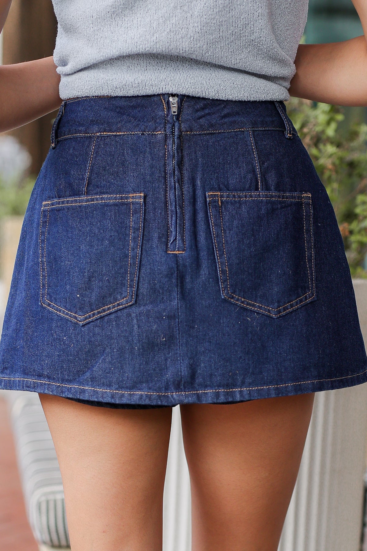 Person wearing a blue denim skirt with a blurred background