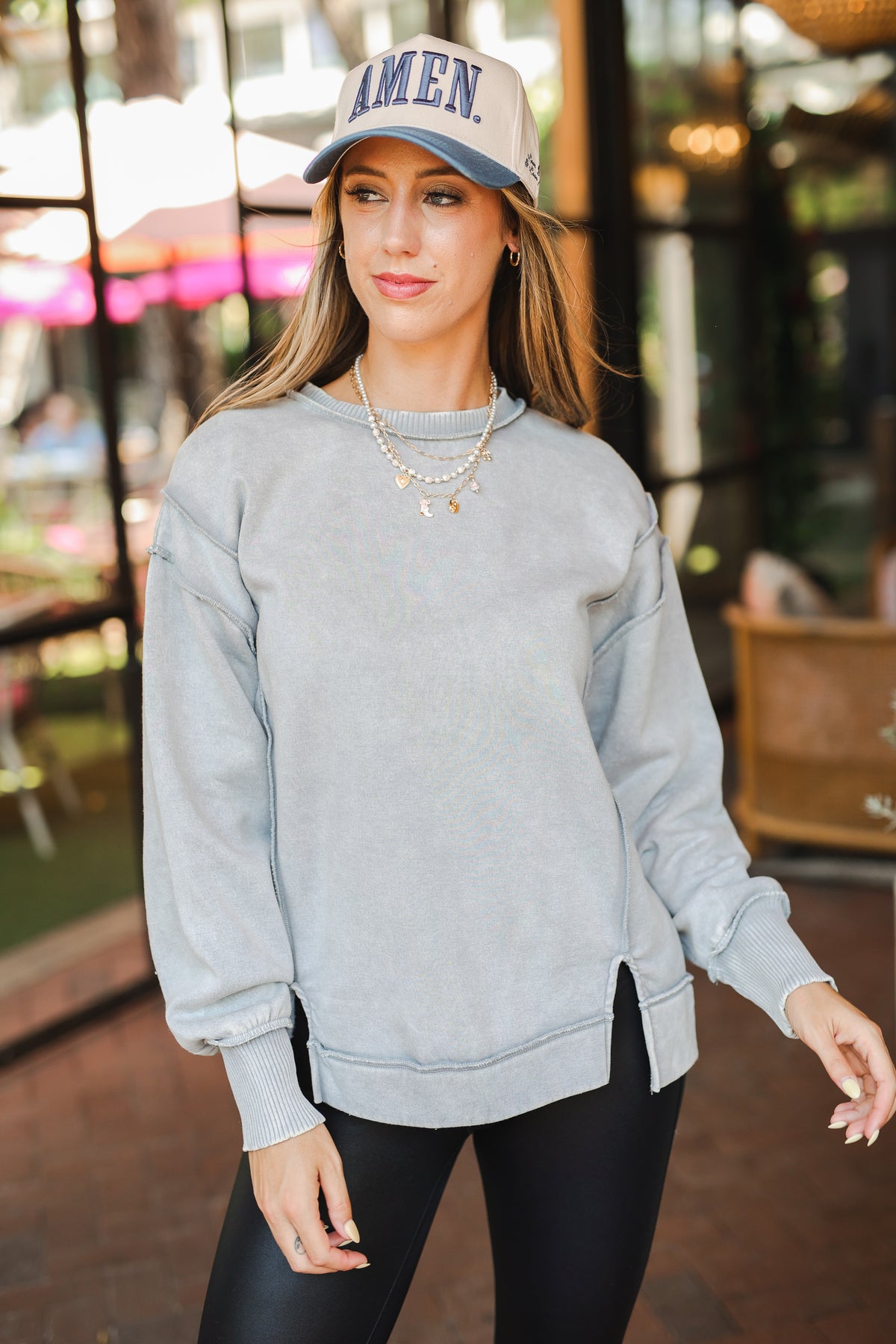 Woman wearing a gray sweatshirt and black leggings with a cap in an outdoor setting