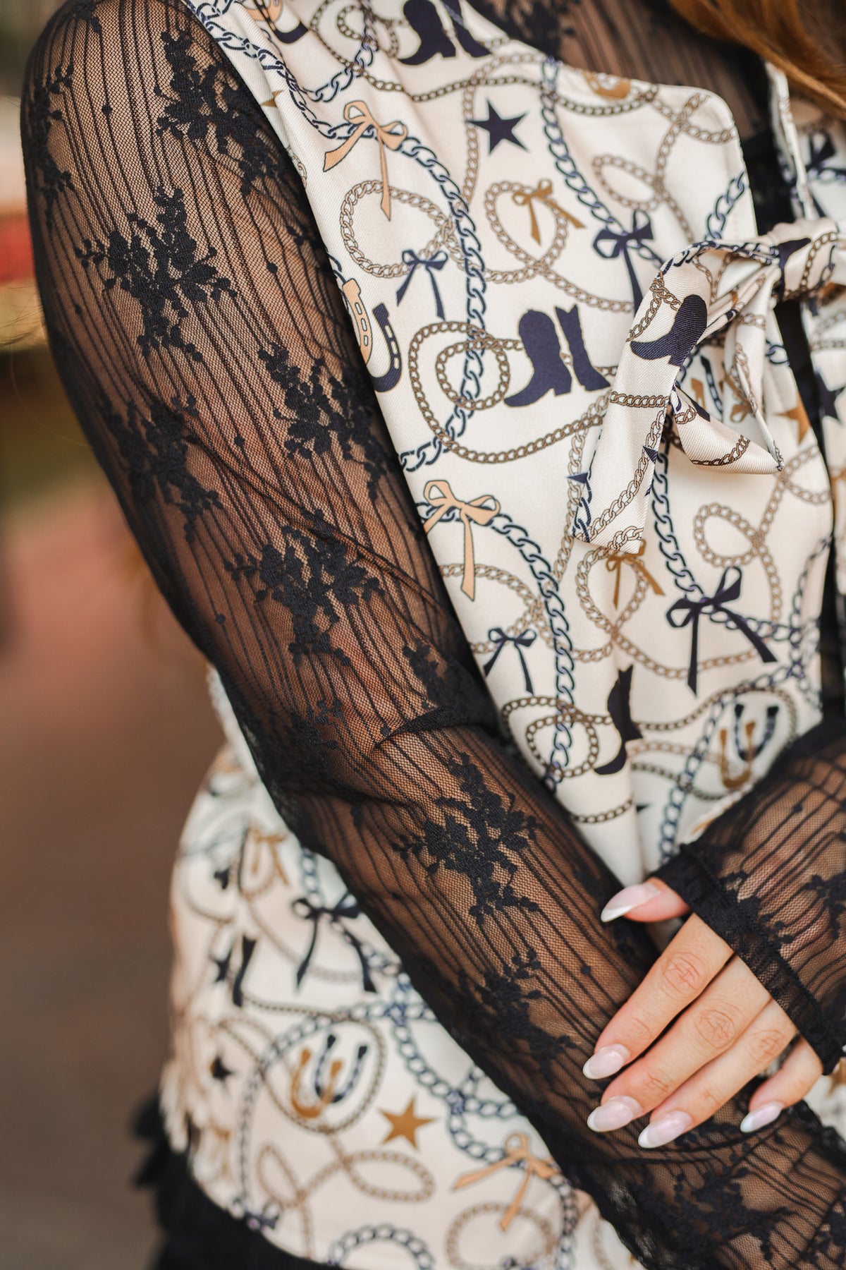 Close-up of a person wearing black lace gloves and a patterned outfit.