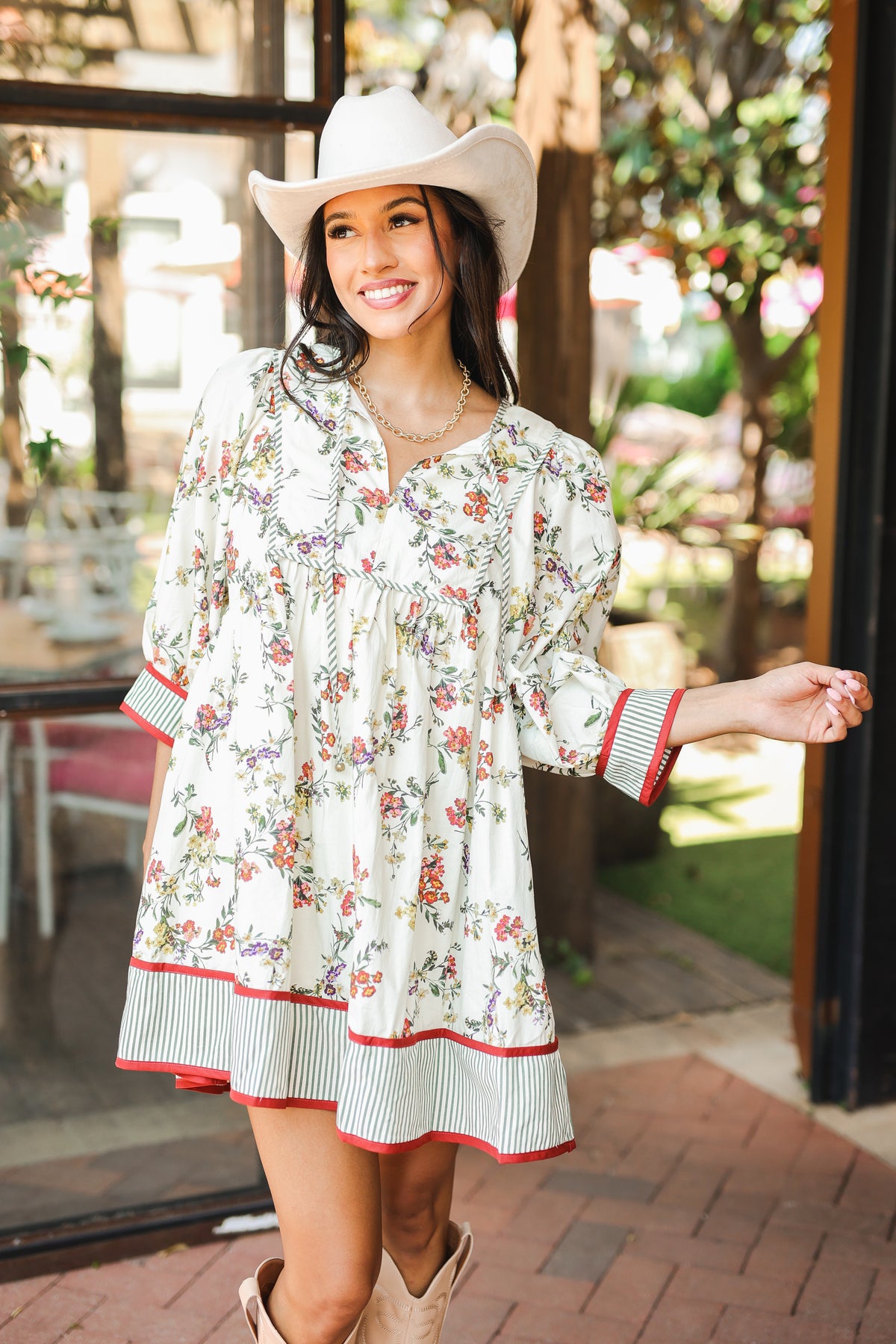 Woman wearing a floral dress and cowboy hat outdoors