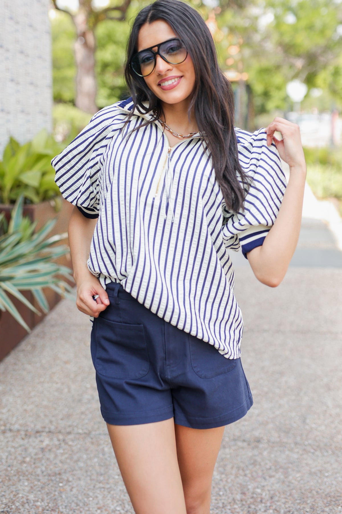 Woman wearing a striped shirt and navy shorts outdoors