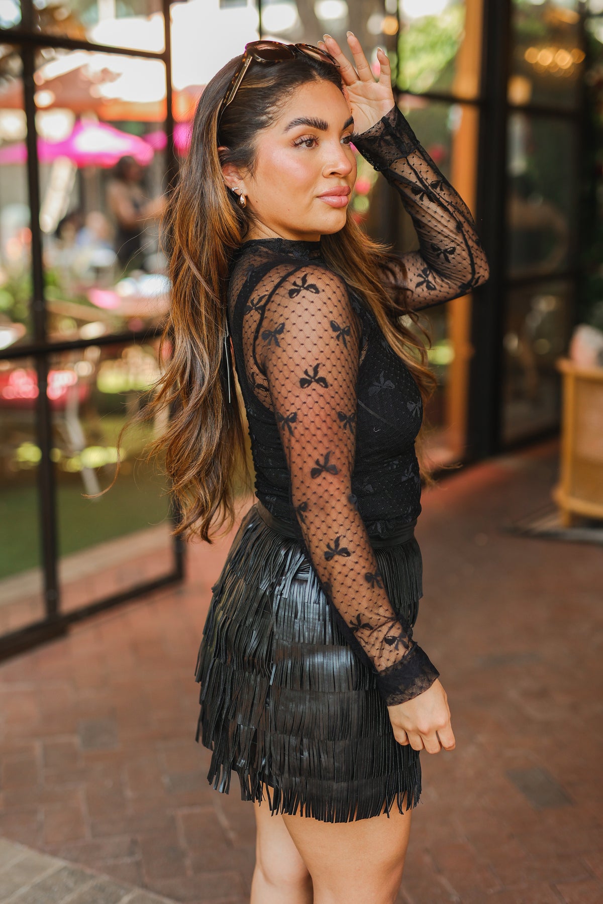Woman wearing a black fringe dress with a lace top in an outdoor setting