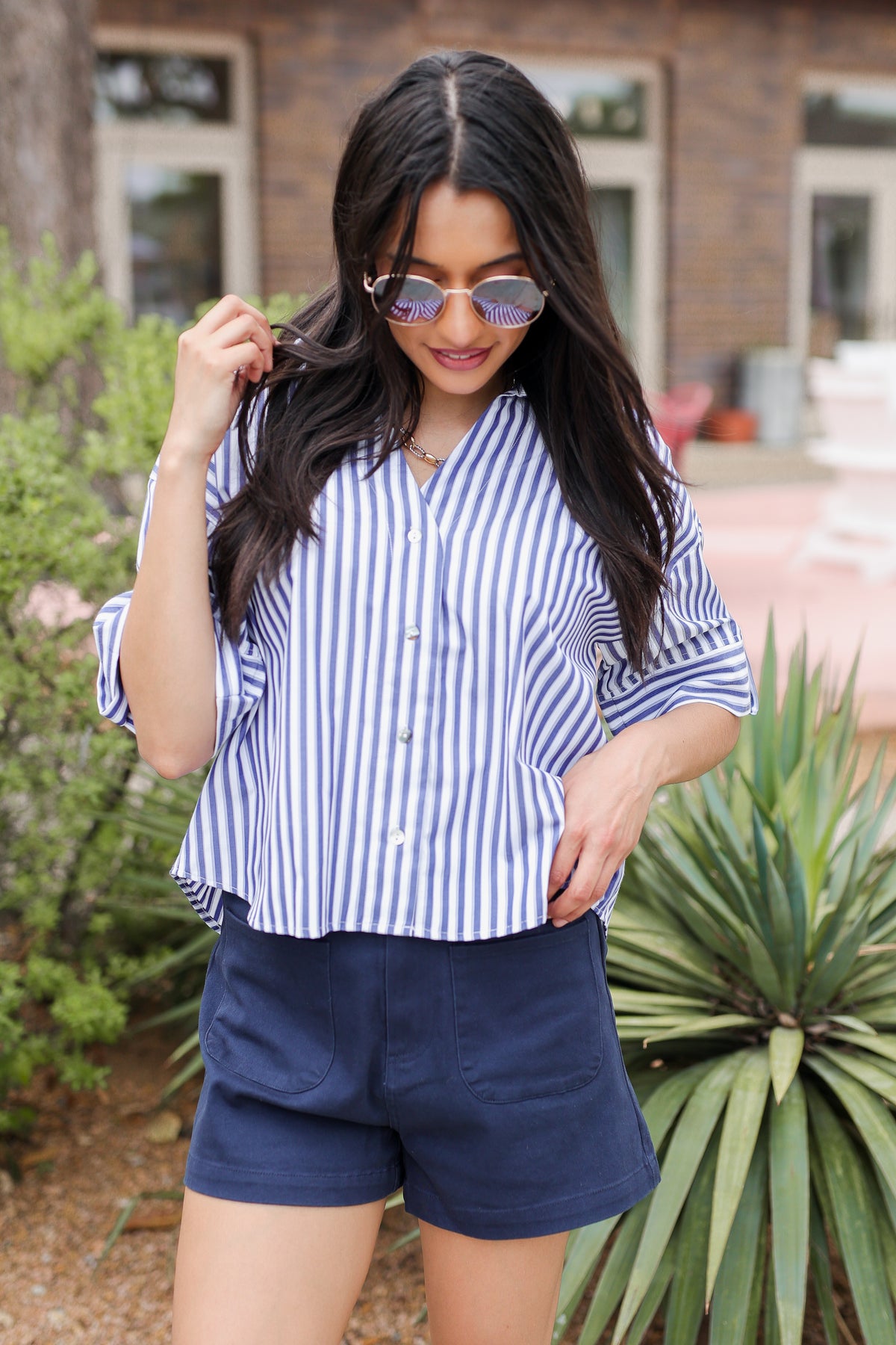 Woman wearing a striped shirt and navy shorts outdoors.