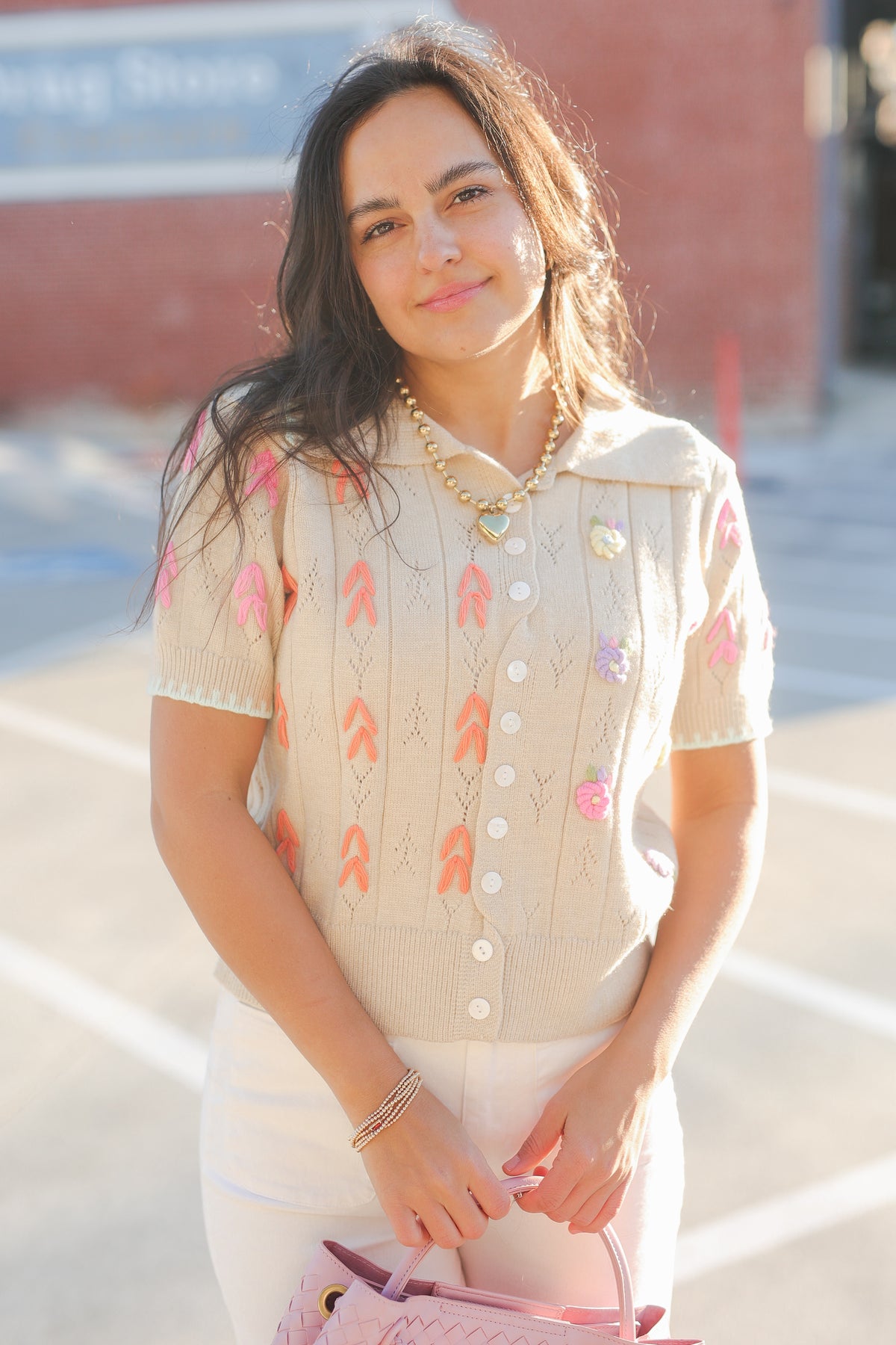 Woman wearing a beige blouse with colorful patterns outdoors.