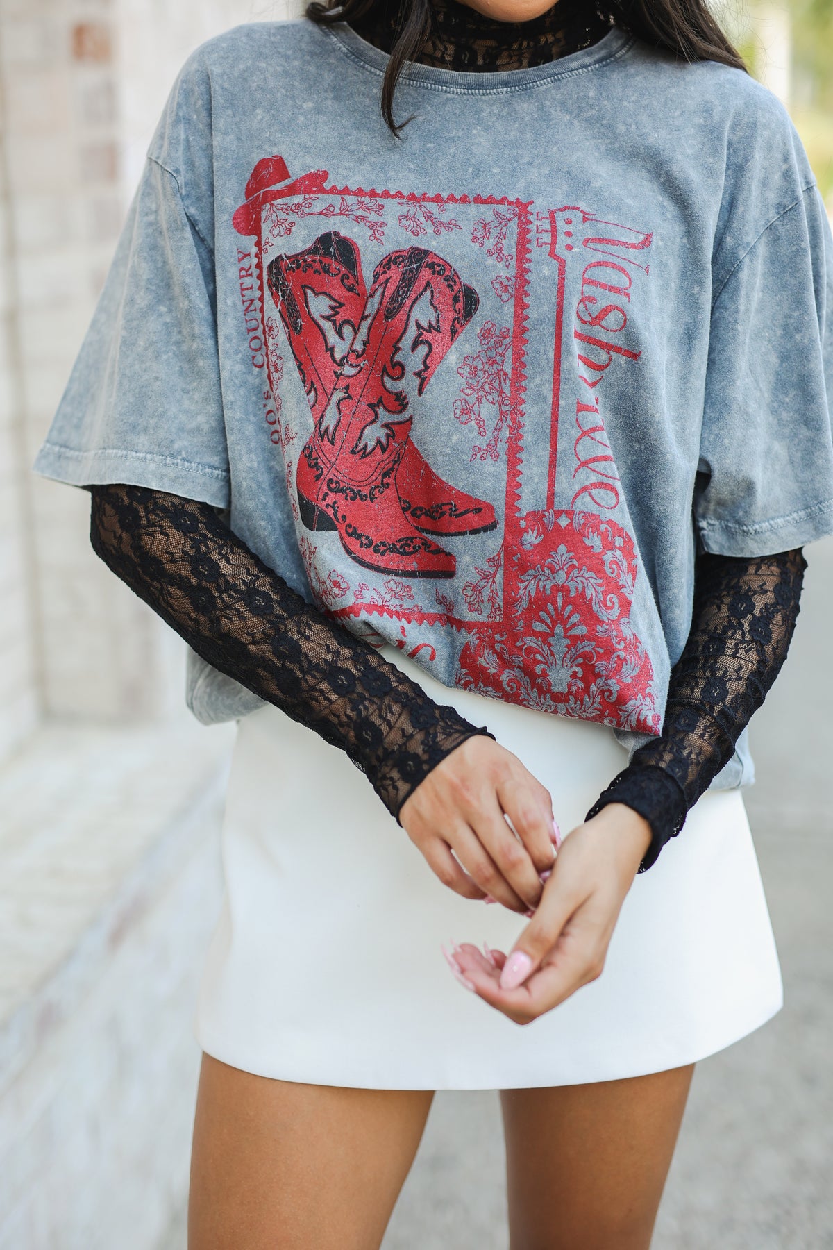 Person wearing a graphic t-shirt with red boots and lace sleeves.