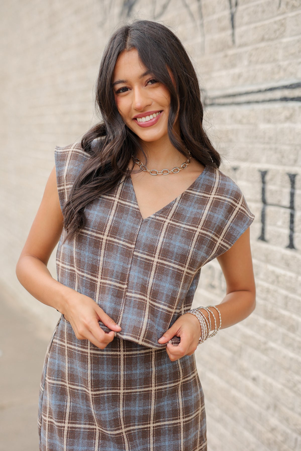 Brunette model wearing a brown and blue sleeveless set and skort with tan boots outside. Southern House Clothing