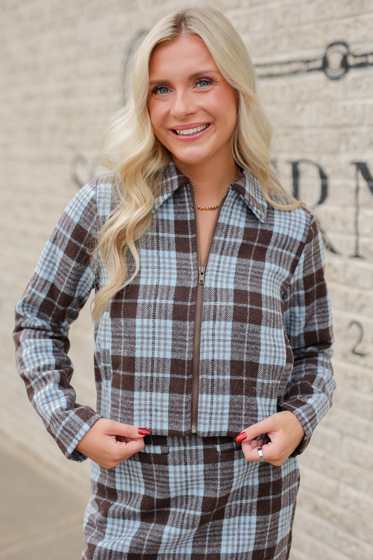 Blonde model standing outside wearing a blue and brown jacket and skirt set. Southern House Clothing