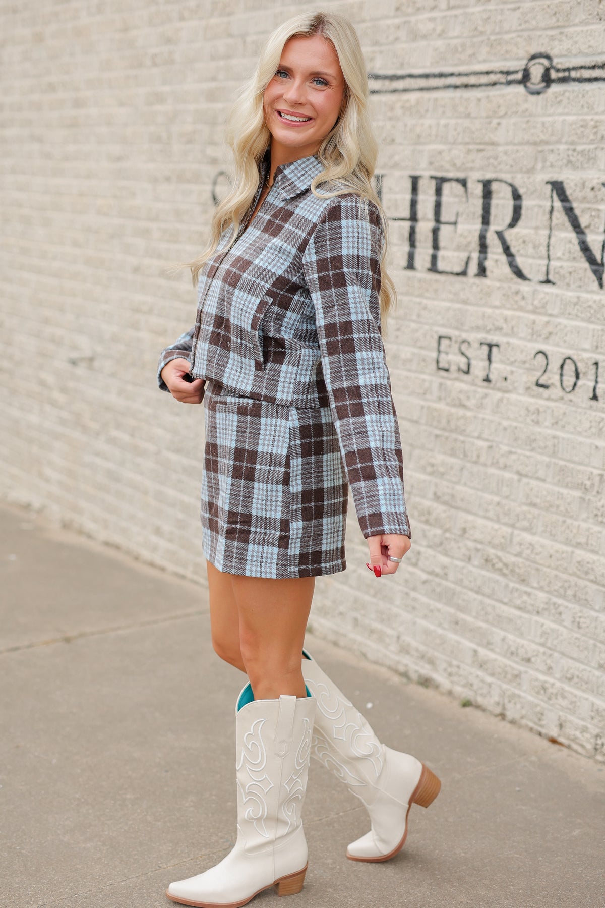 Blonde model standing outside wearing a blue and brown jacket and skirt set. Southern House Clothing