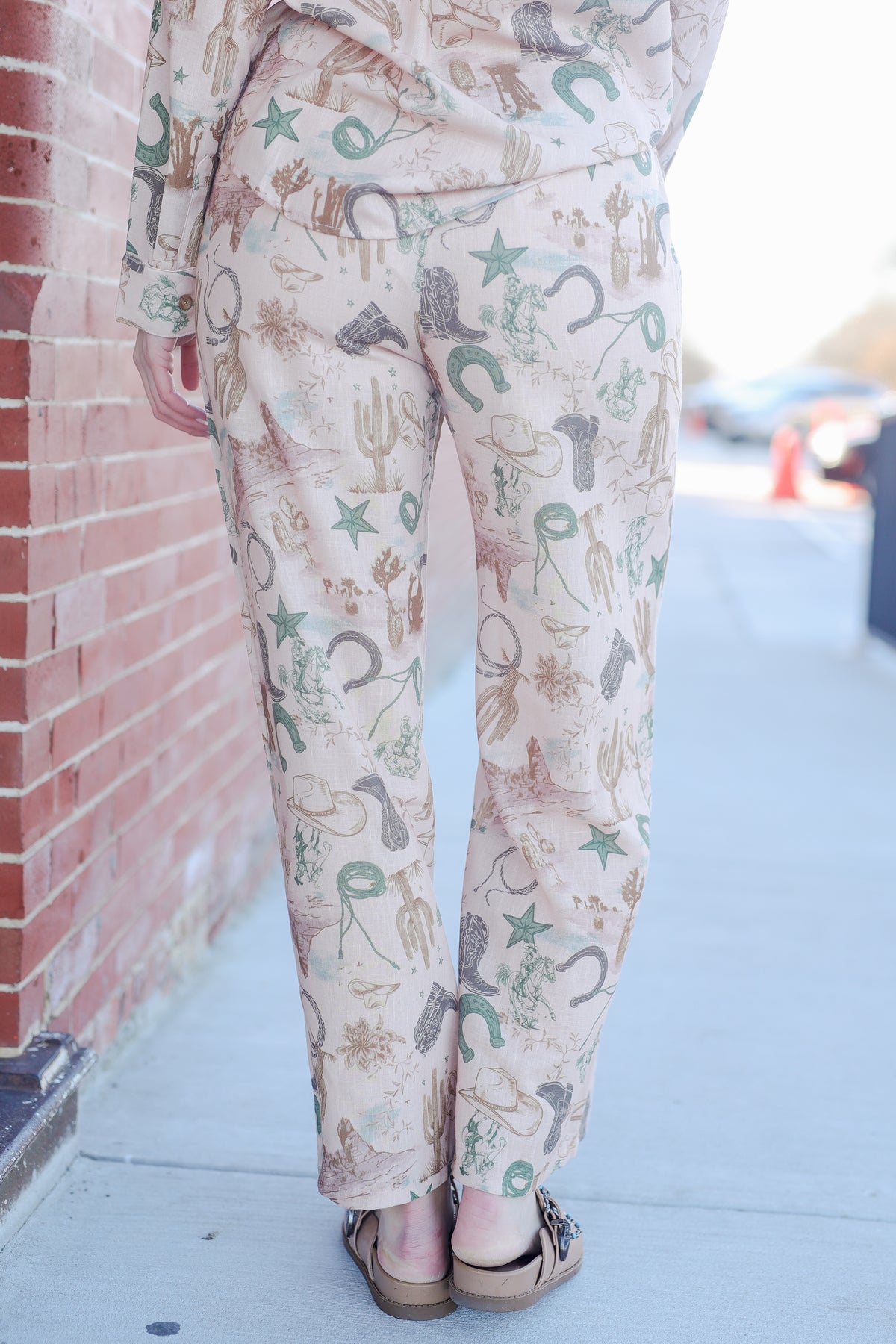 Person wearing patterned pants with a brick wall and blurred background