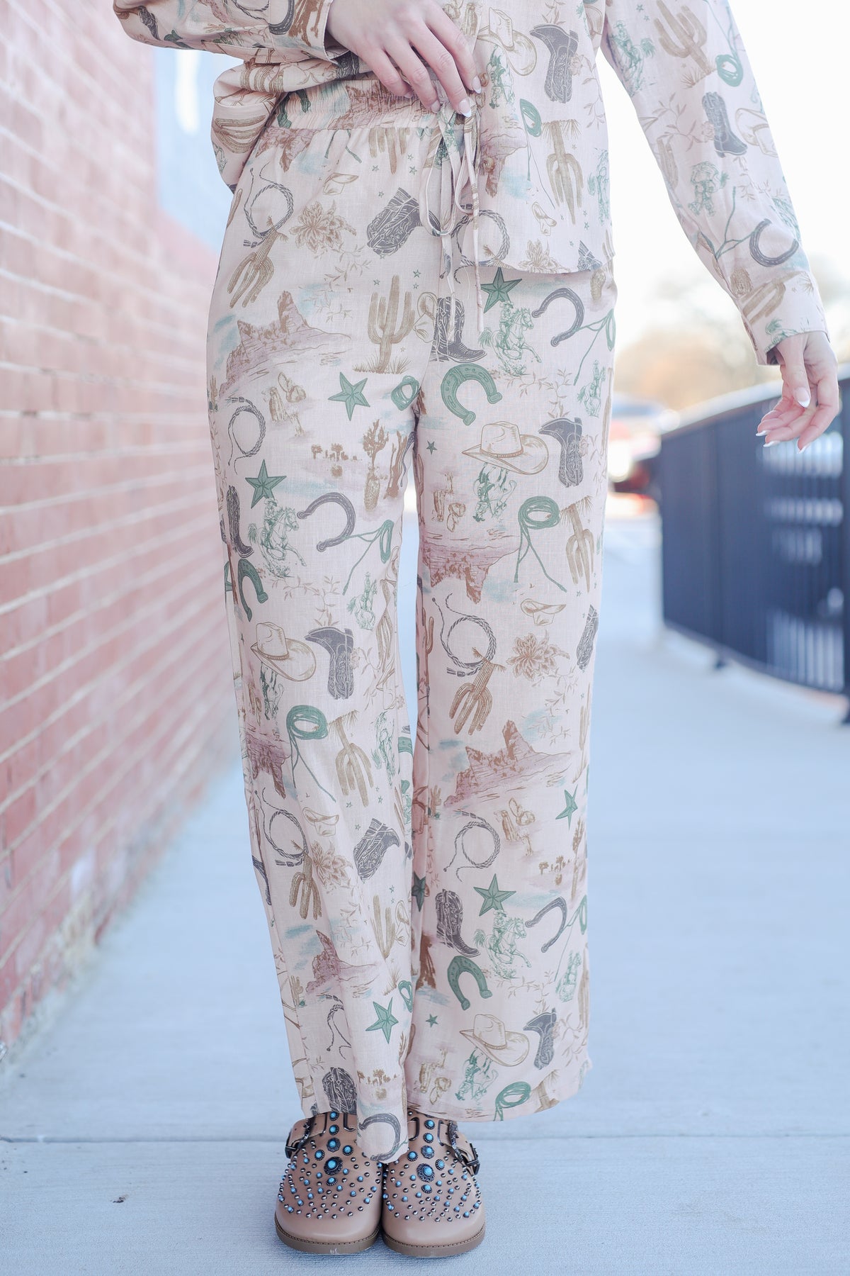 Person wearing a patterned outfit with a pink wall and white ground in the background