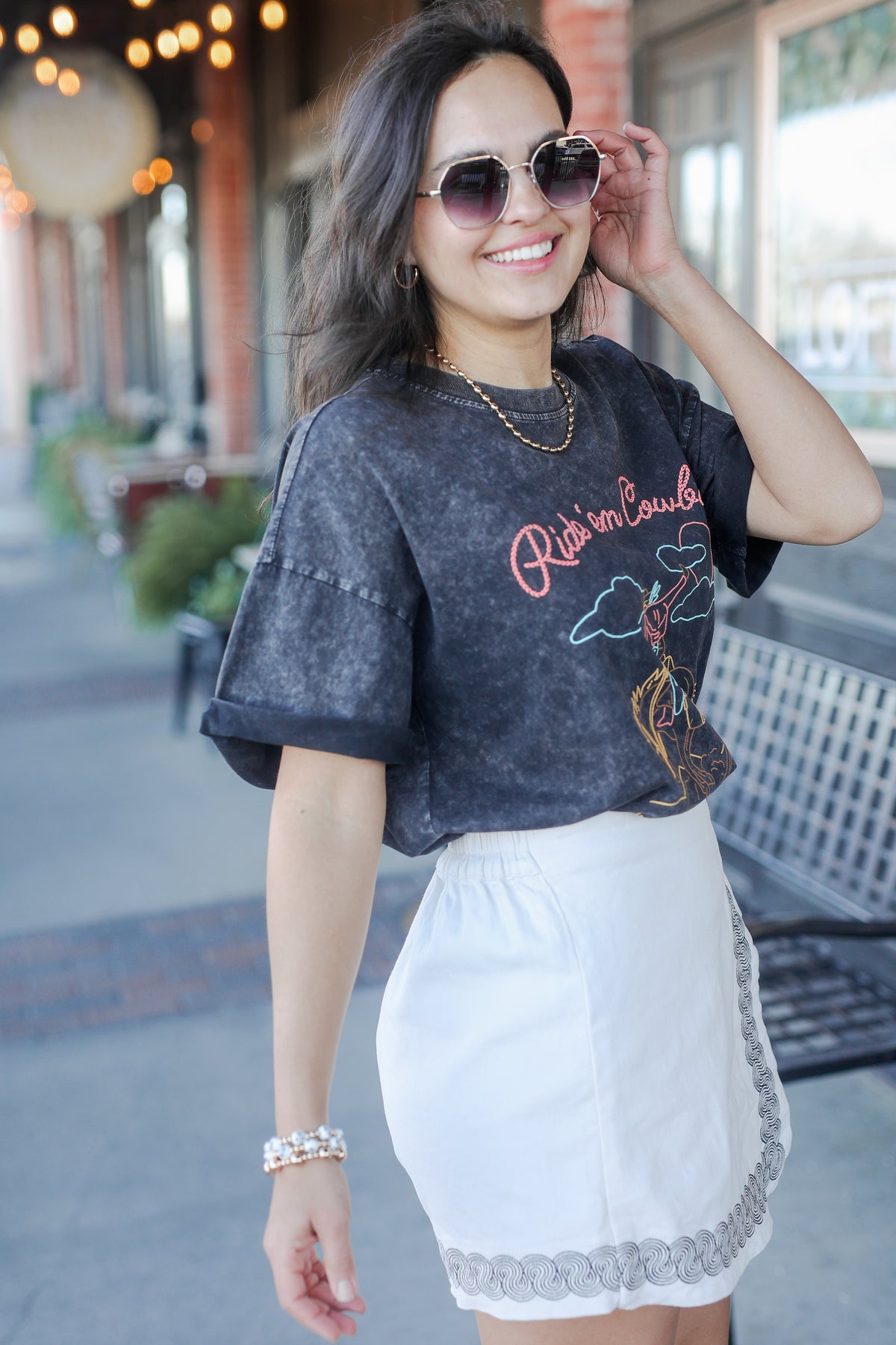 Woman wearing a dark graphic t-shirt and white skirt outdoors