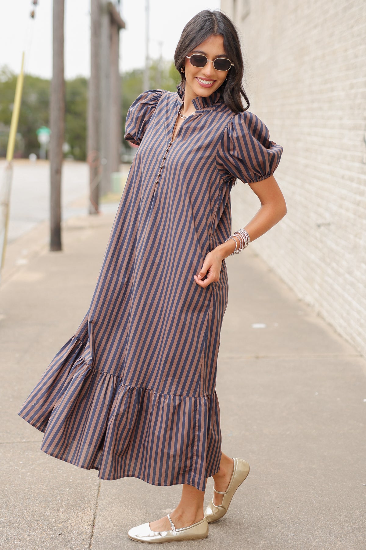 Brunette model wearing a navy and brown dress standing outside. Southern House Clothing
