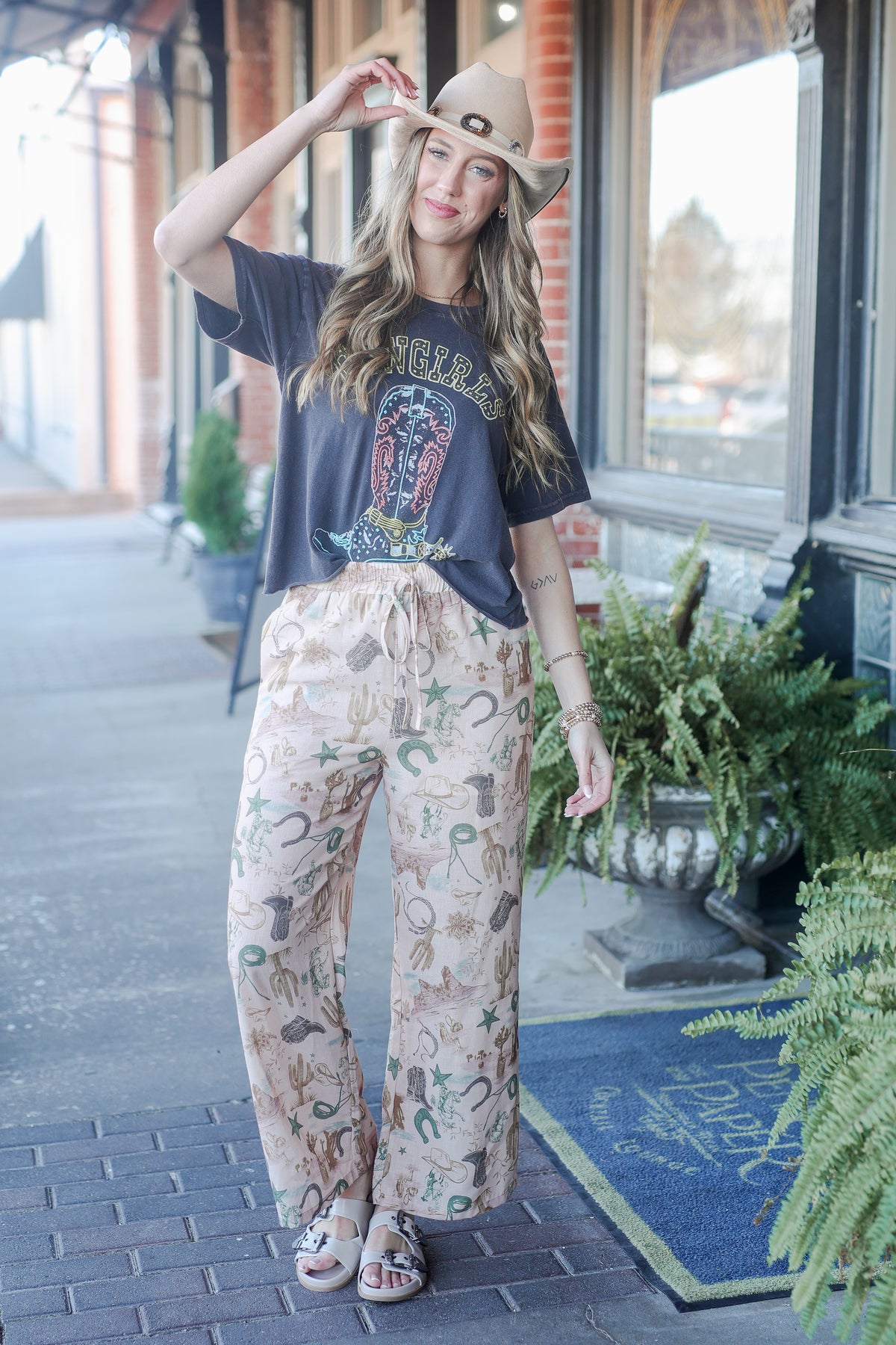 Woman wearing a graphic t-shirt and patterned pants outdoors.