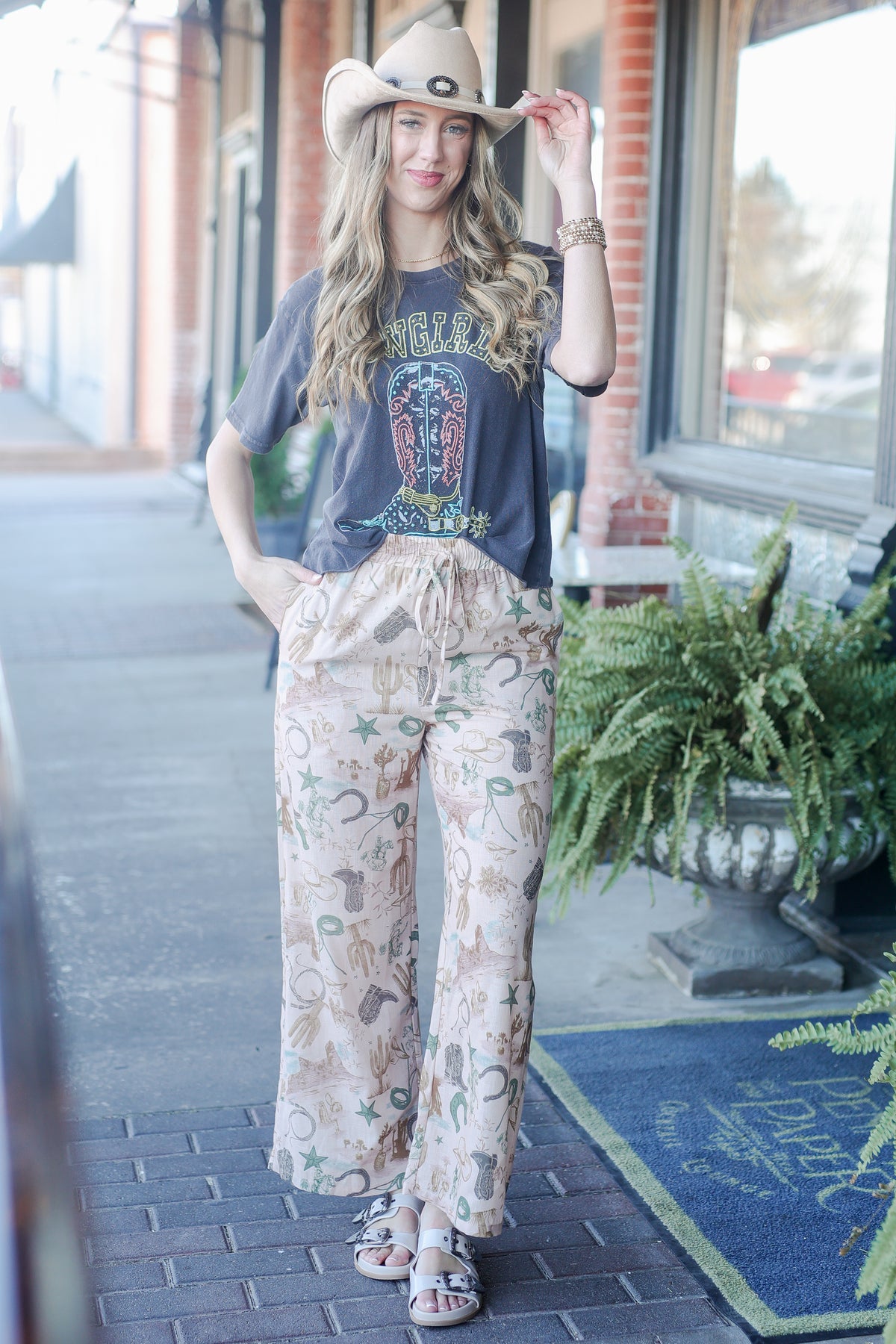 Woman wearing a graphic t-shirt and patterned pants on a sidewalk.