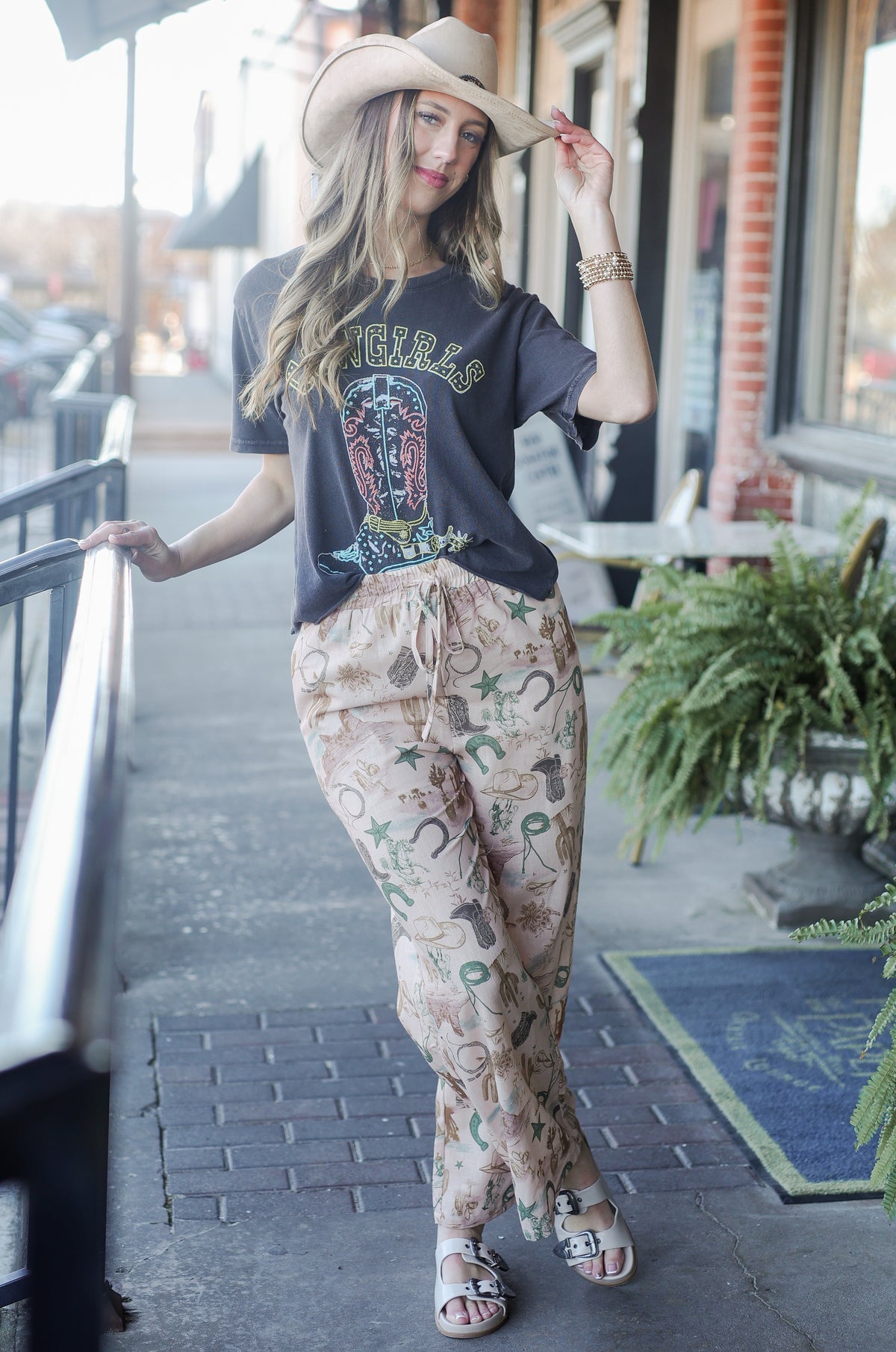 Woman wearing a graphic t-shirt and patterned pants outdoors.