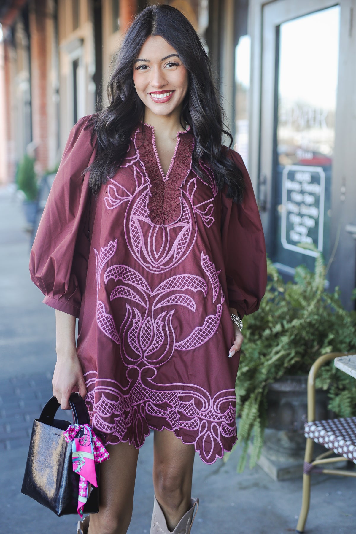 Woman wearing a burgundy dress with white patterns outdoors.