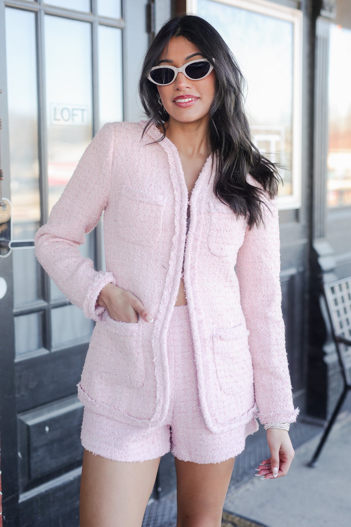 Woman wearing a pink quilted jacket and shorts set in an urban setting.