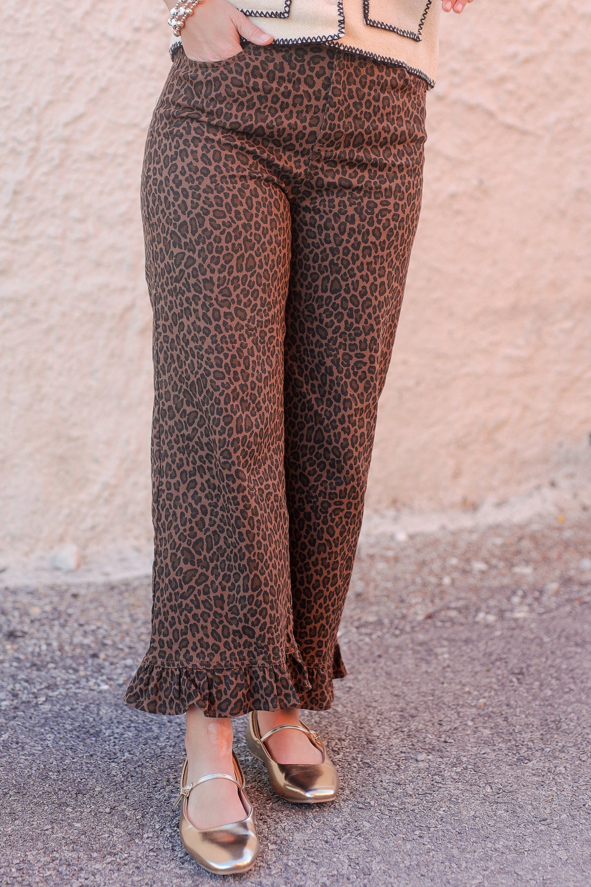 Person wearing leopard print pants with a neutral background