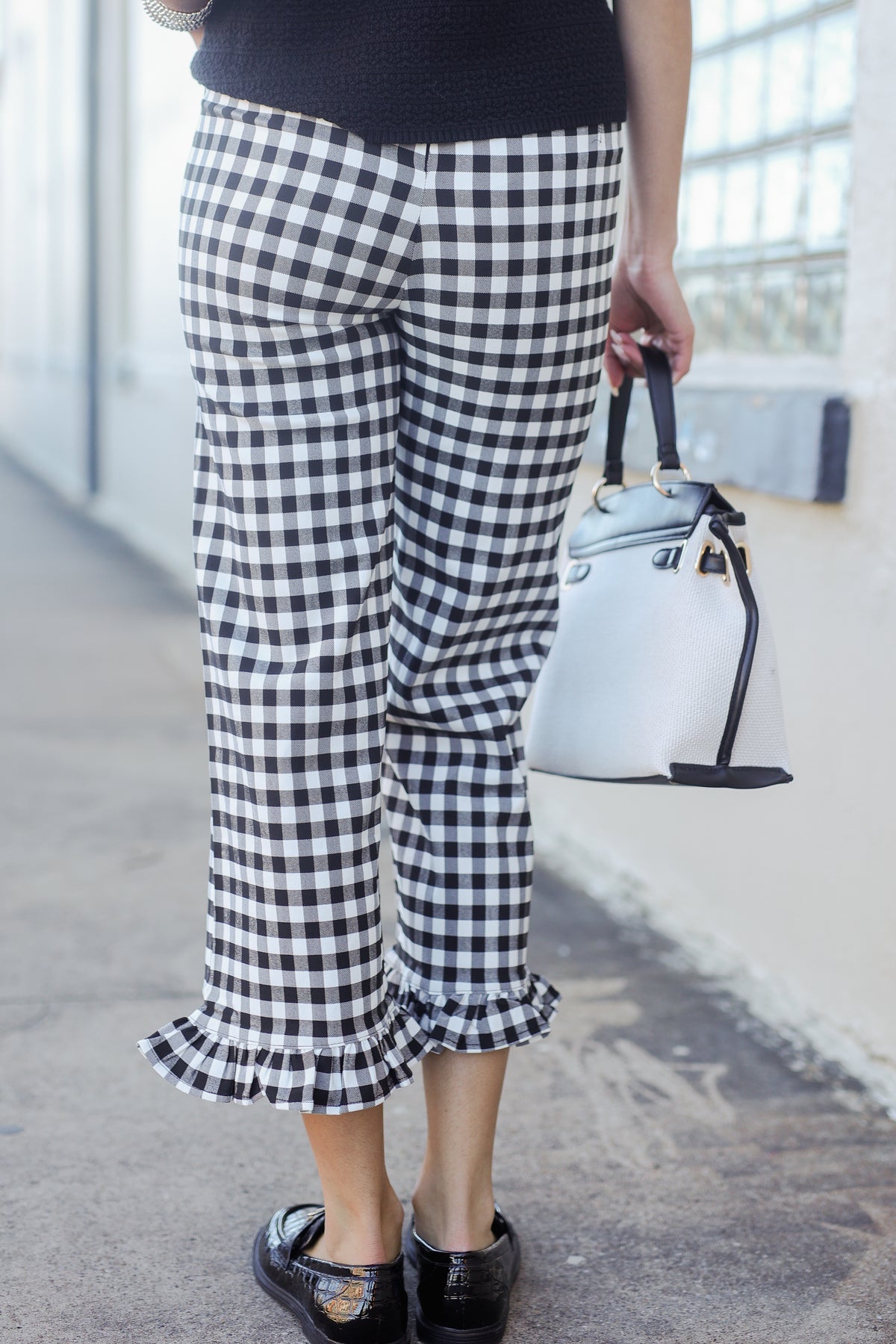 Person wearing black and white checkered pants with a light blue handbag.