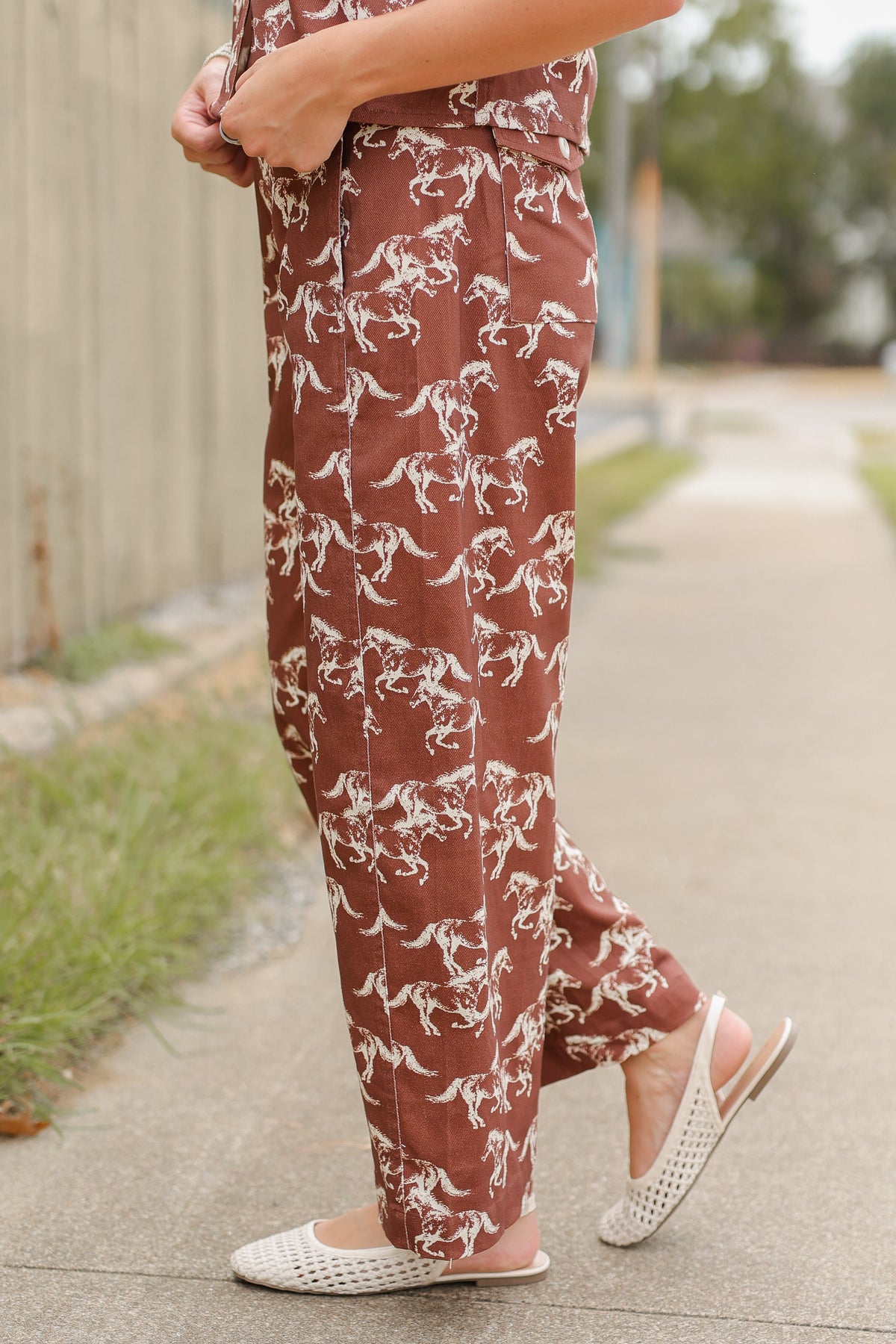 Blonde model wearing the Cibolo Running Horses Button-Up Top – Brown and matching denim bottoms - Cibolo Running Horses Wide Leg Pants – Brown standing outside. Southern House Clothing
