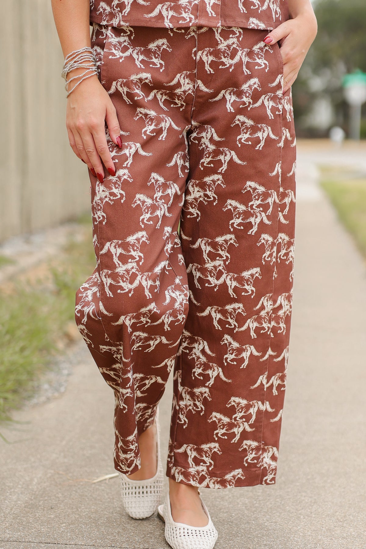 Blonde model wearing the Cibolo Running Horses Button-Up Top – Brown and matching denim bottoms - Cibolo Running Horses Wide Leg Pants – Brown standing outside. Southern House Clothing