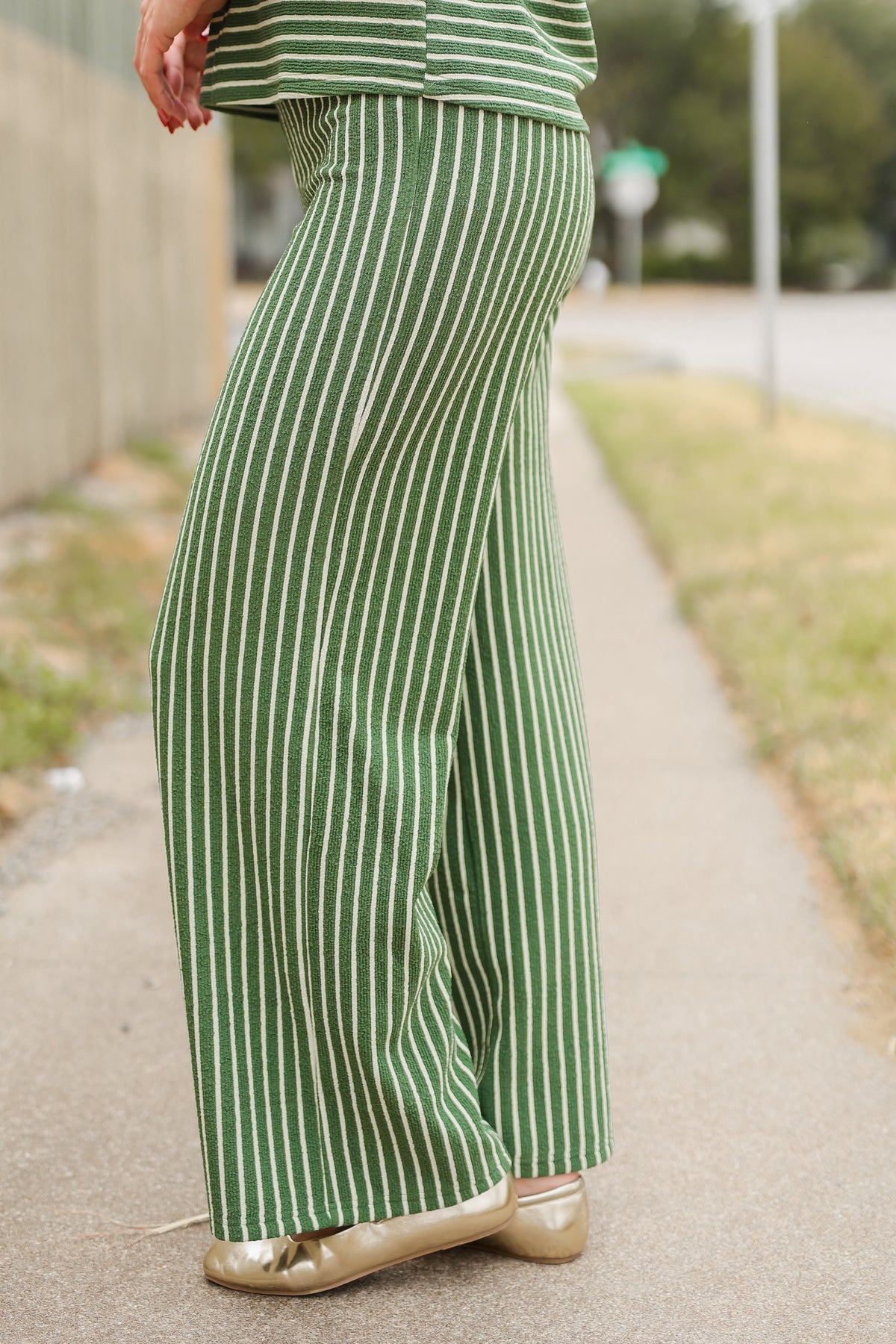Close up of the pants of an olive set worn by a model outside. Southern House Clothing