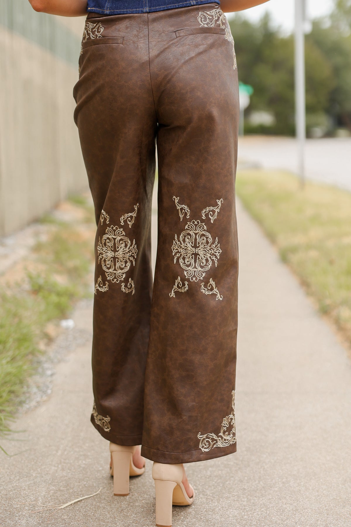 Close up showing the details of a brown faux leather pant on a model outside. Southern House Clothing