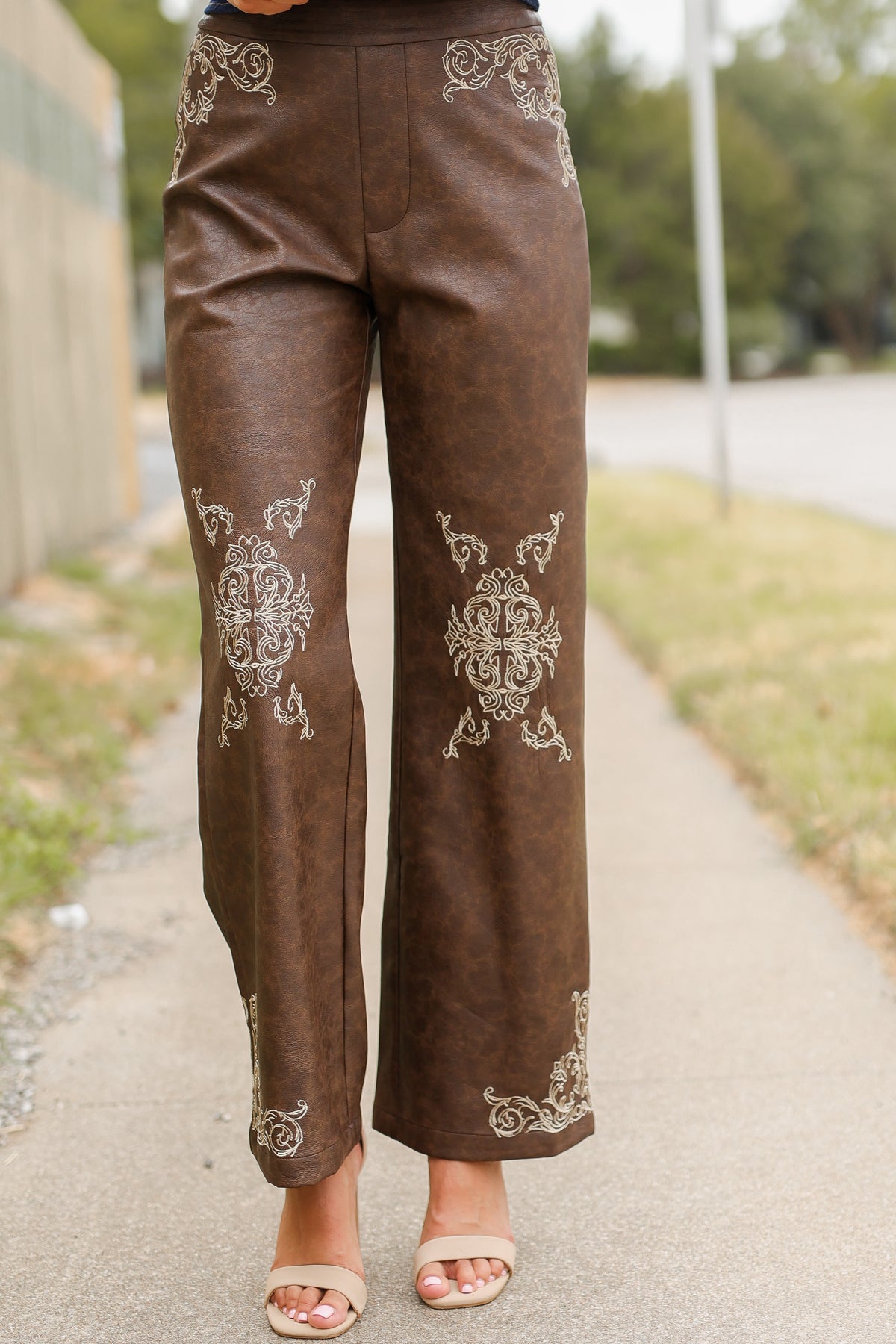 Close up showing the details of a brown faux leather pant on a model outside. Southern House Clothing