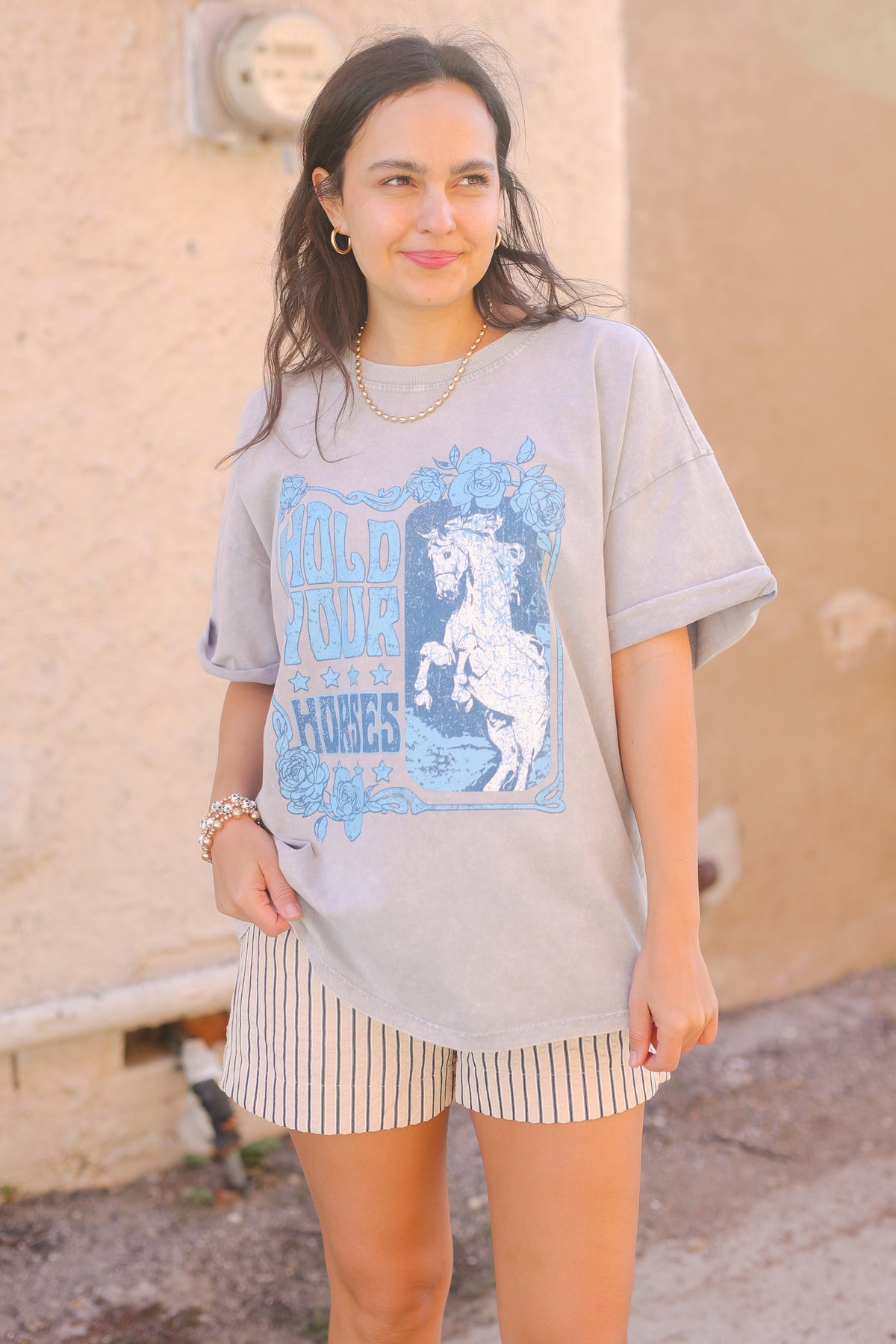 Woman wearing a graphic t-shirt with a horse design outdoors.