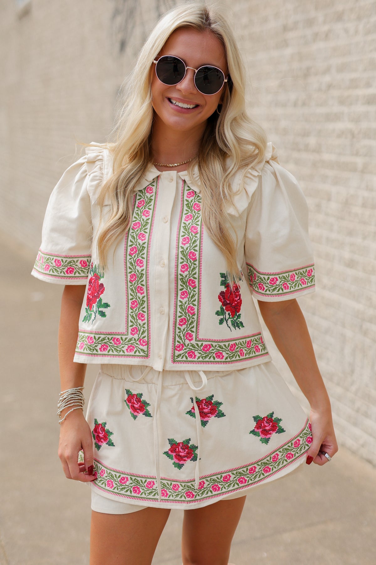 Blonde model wearing a embroidered set with roses and tan jeans standing outside. Southern House Clothing