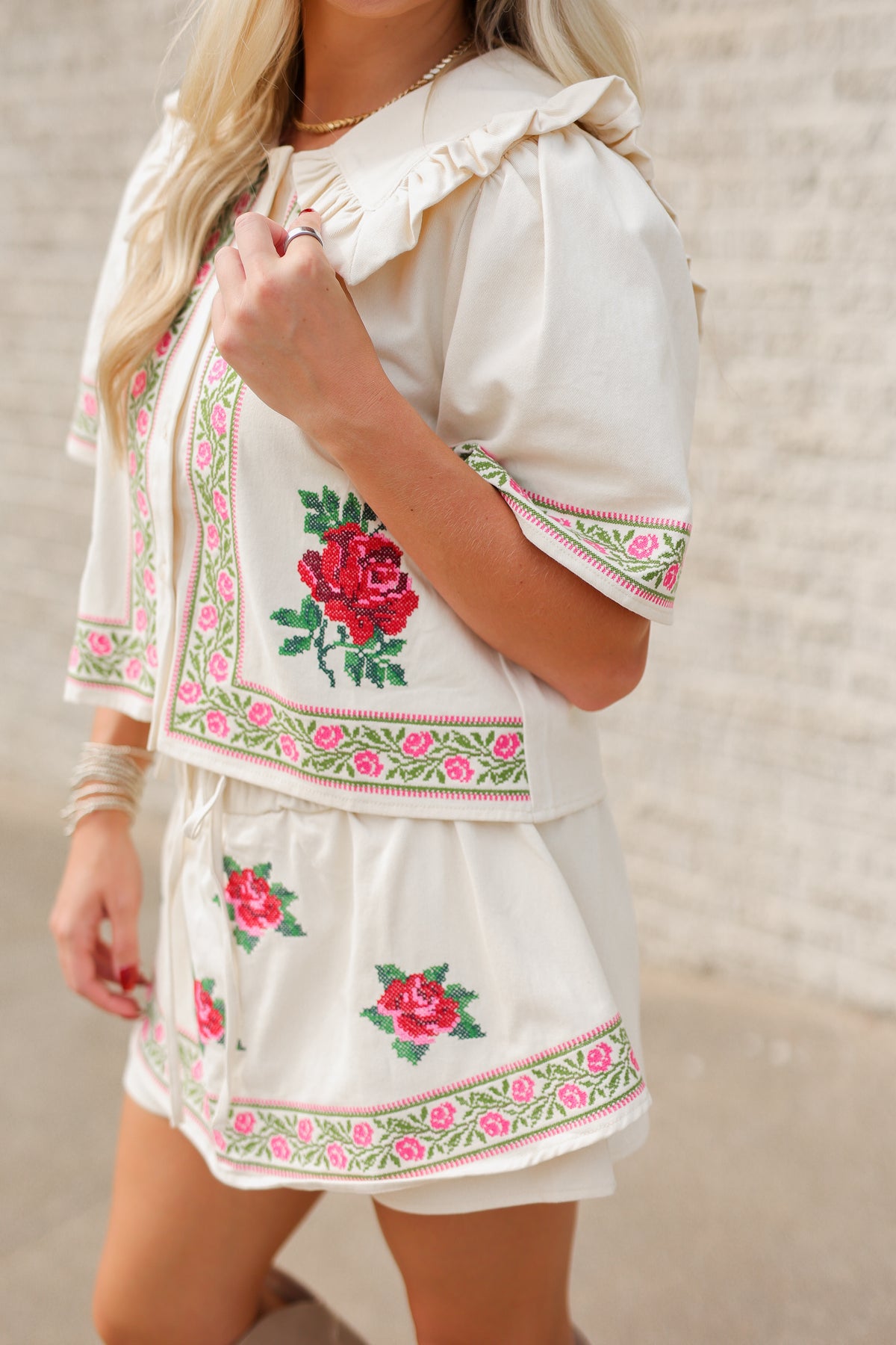 Blonde model wearing a embroidered set with roses and tan jeans standing outside. Southern House Clothing