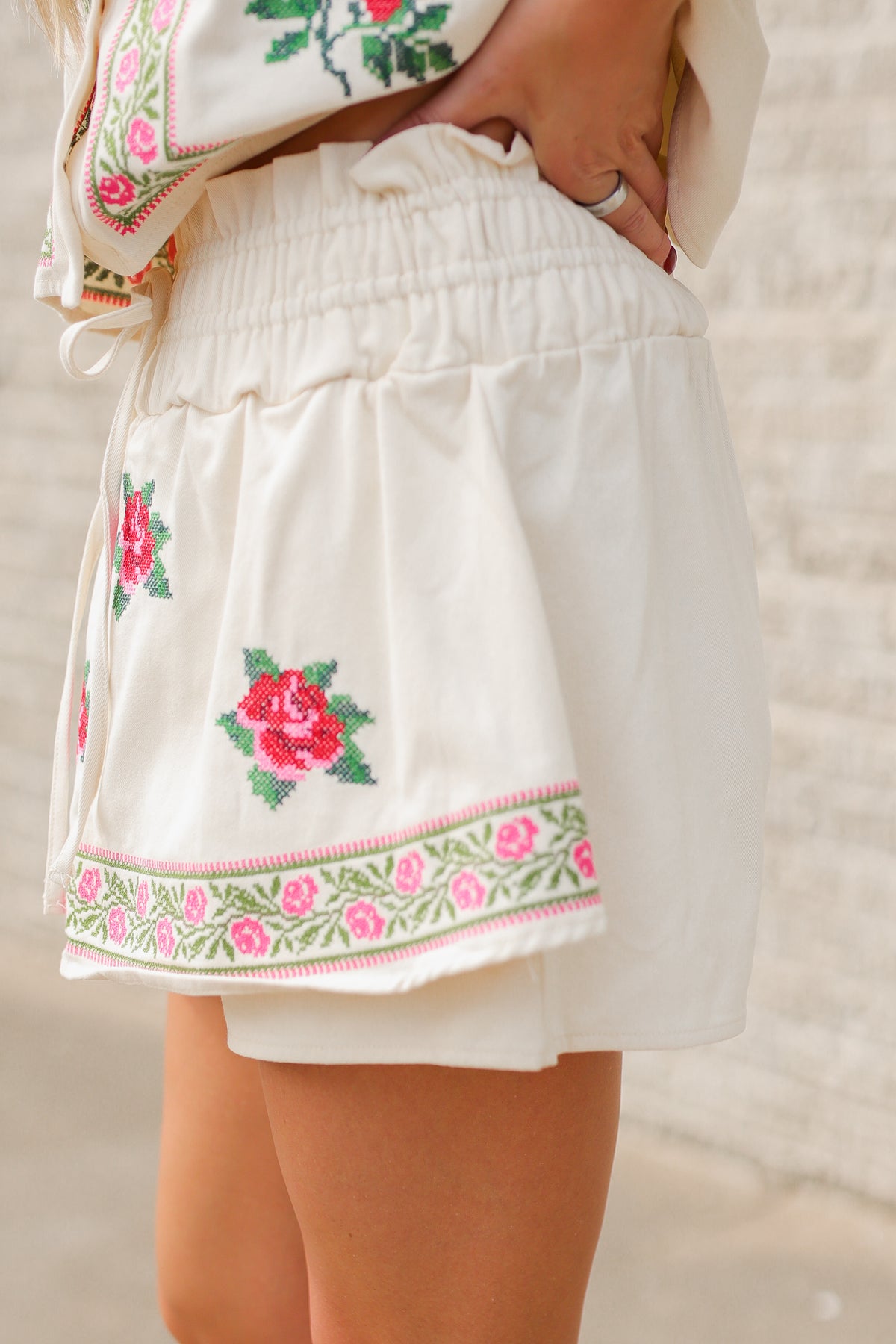 Blonde model wearing a embroidered set with roses and tan jeans standing outside. Southern House Clothing