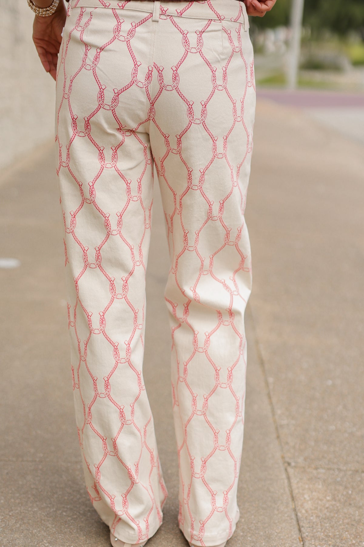 Close-up of Equestrian Charm Horseshoe Print Pants in Ivory/Pink featuring pink horseshoe and rope motifs, belt loops, front pockets, and button closure. Southern House Clothing