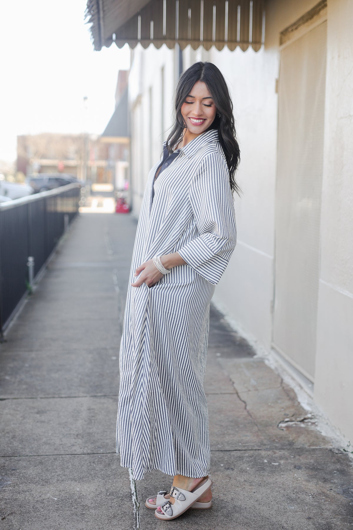 Woman wearing a long, thin striped dress on a city street.