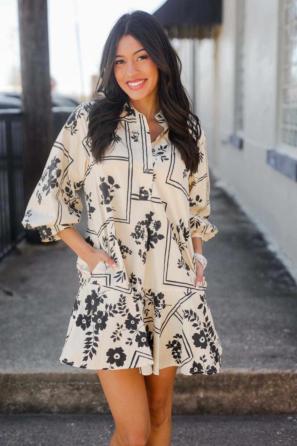 Woman wearing a floral dress standing outdoors.