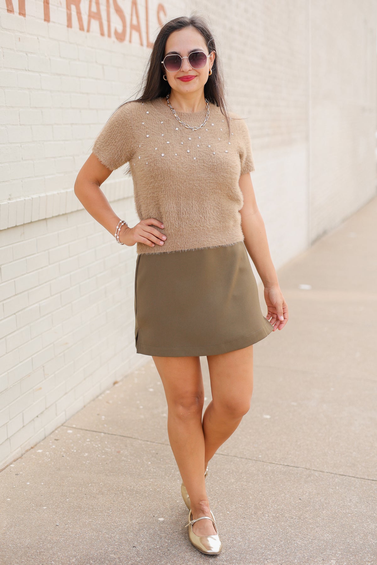 Model wearing the Liora Pearl Knit Top in Mocha with pearl-inspired embellishments and fuzzy knit texture, paired with the Winsford Mini Skort in Olive. Southern House Clothing