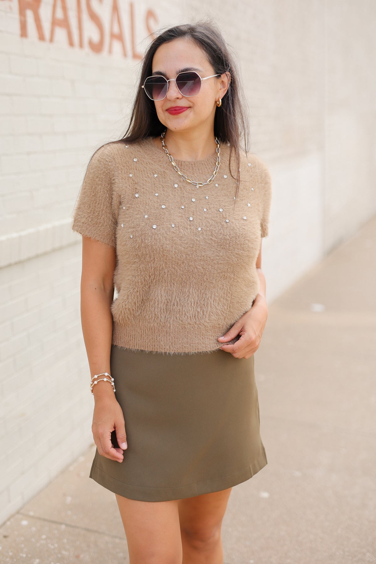 Model wearing the Liora Pearl Knit Top in Mocha with pearl-inspired embellishments and fuzzy knit texture, paired with the Winsford Mini Skort in Olive. Southern House Clothing