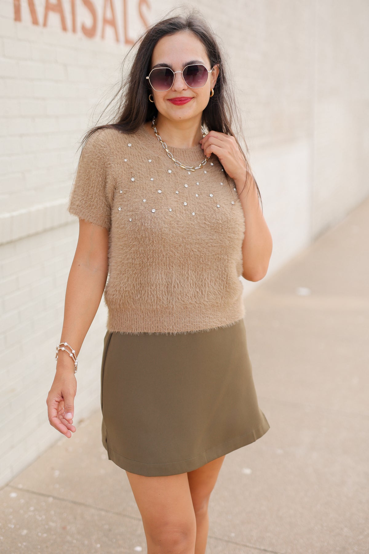 Model wearing the Liora Pearl Knit Top in Mocha with pearl-inspired embellishments and fuzzy knit texture, paired with the Winsford Mini Skort in Olive. Southern House Clothing