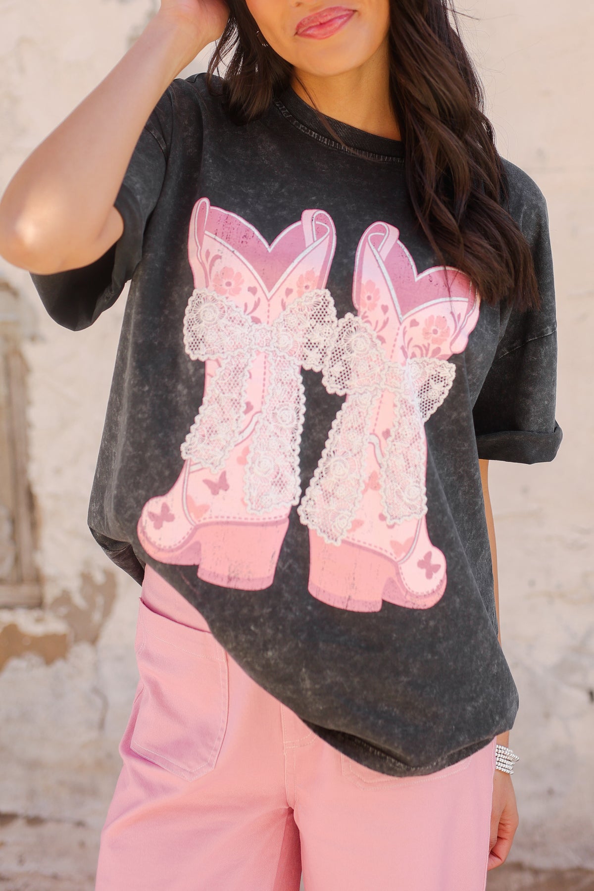 Person wearing a dark gray t-shirt with pink bunny graphics and pink pants against a light background