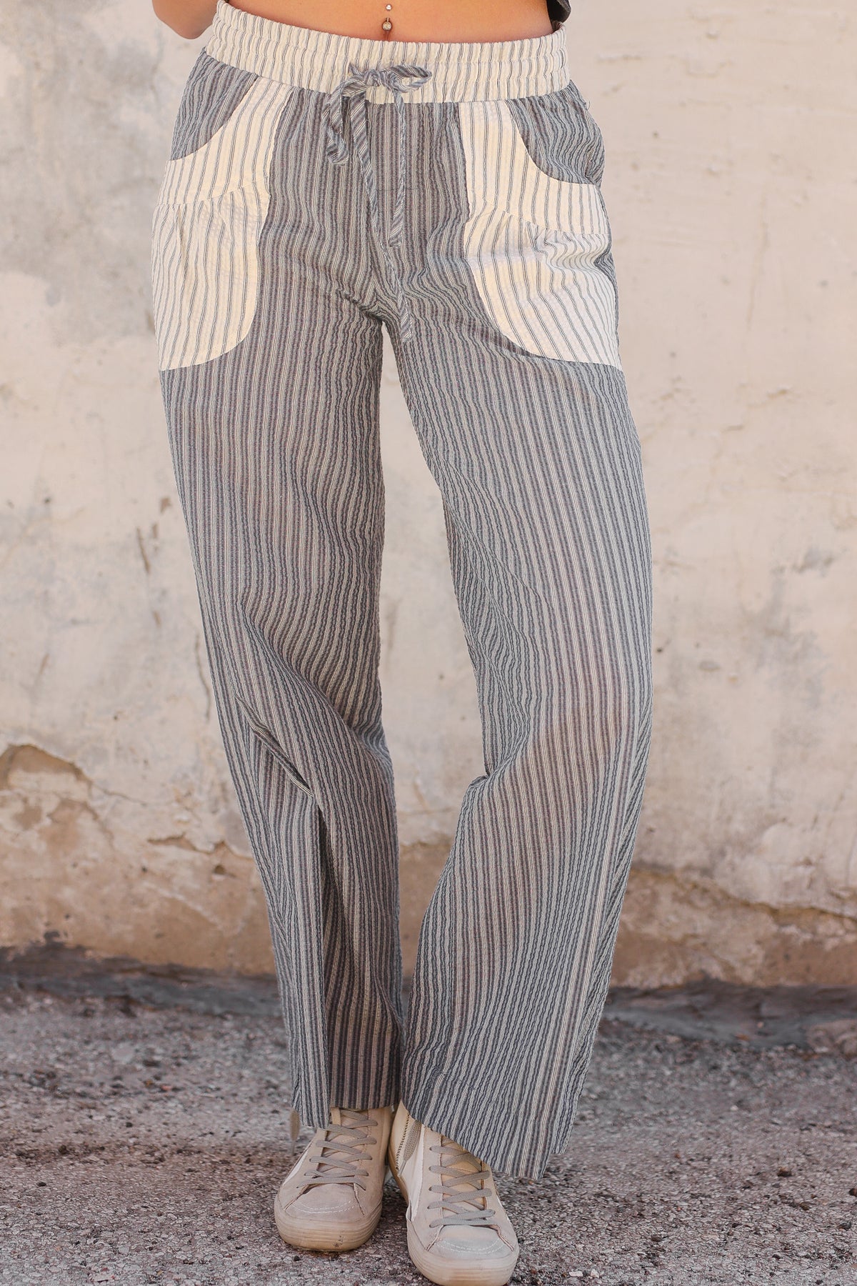 Striped pants worn by a person against a textured wall.